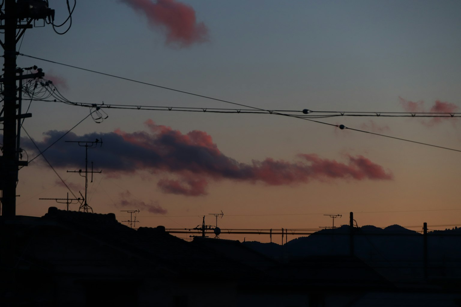Sonnenuntergangshimmel mit silhouettierten Bergen Stromleitungen und Masten im Blick