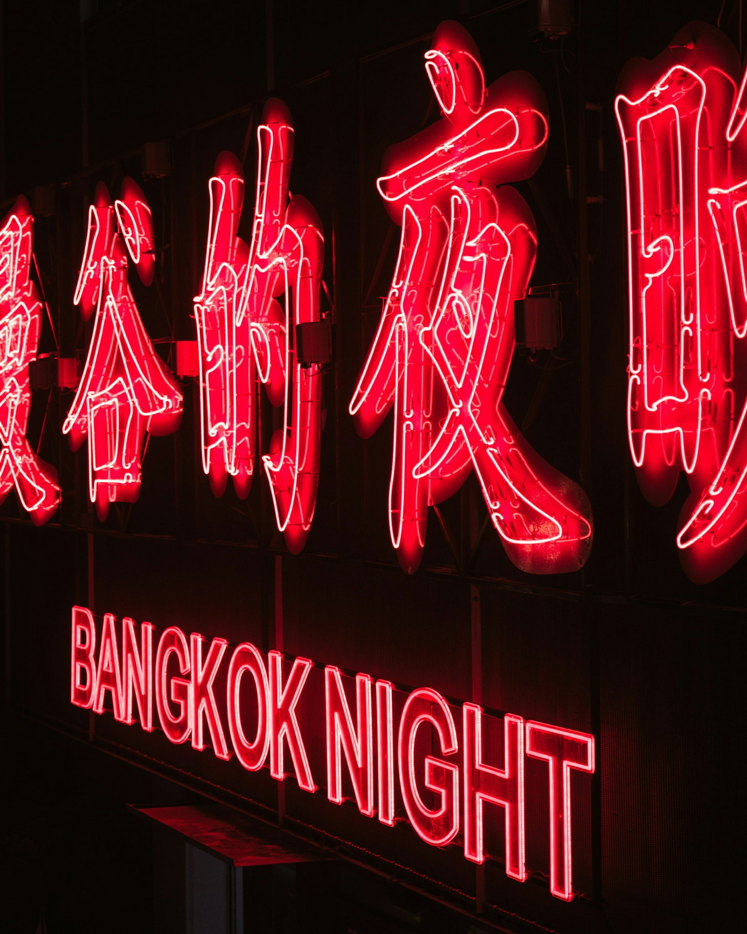 Neon sign in Bangkok featuring bright red characters and the text Bangkok Night