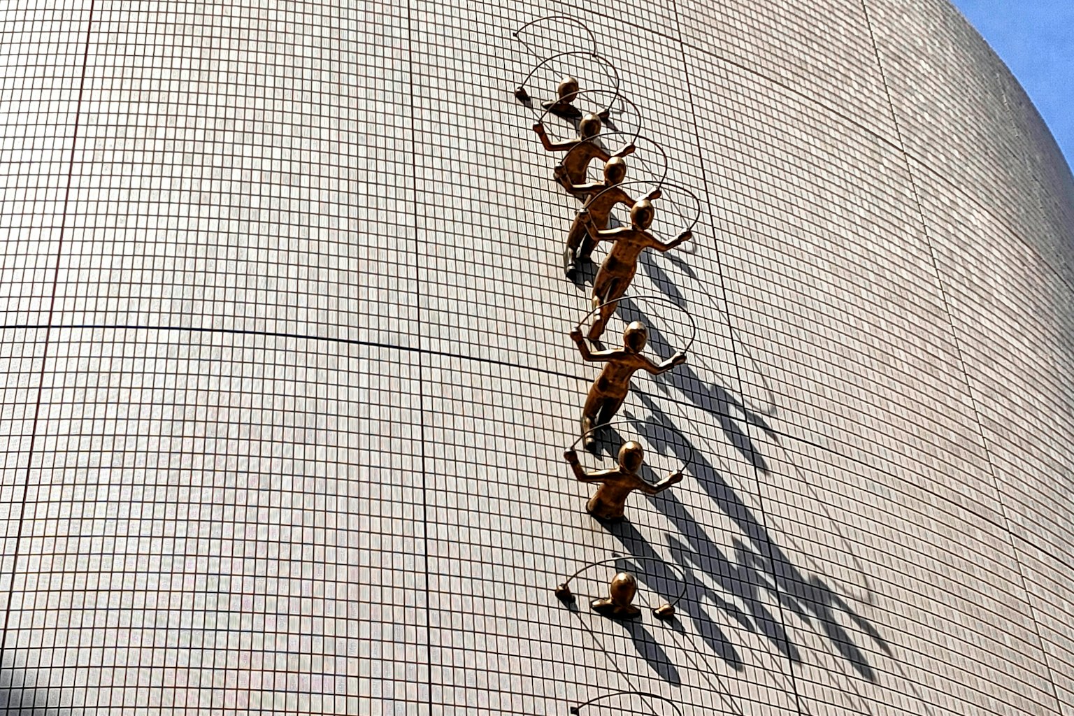 Groupe de sculptures grimpant sur un mur avec des ombres