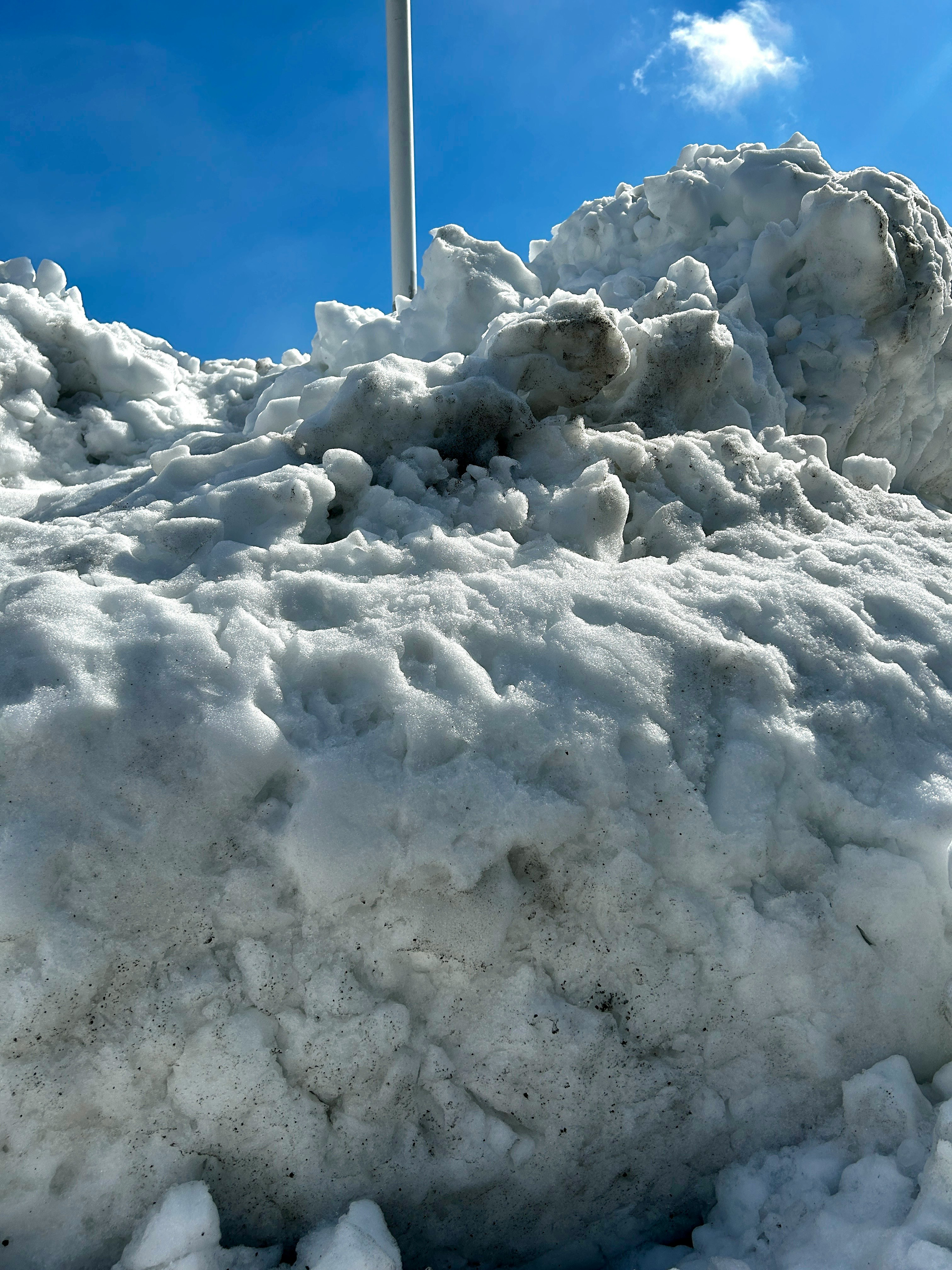 積み上がった雪と青空の下の雪かき