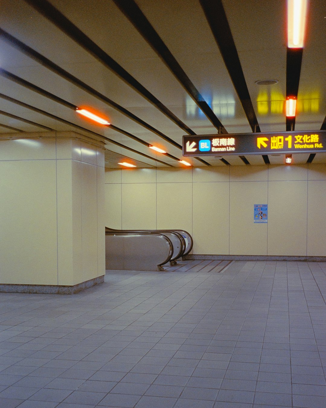 地下鉄の通路に並ぶ案内標識と照明のある駅構内