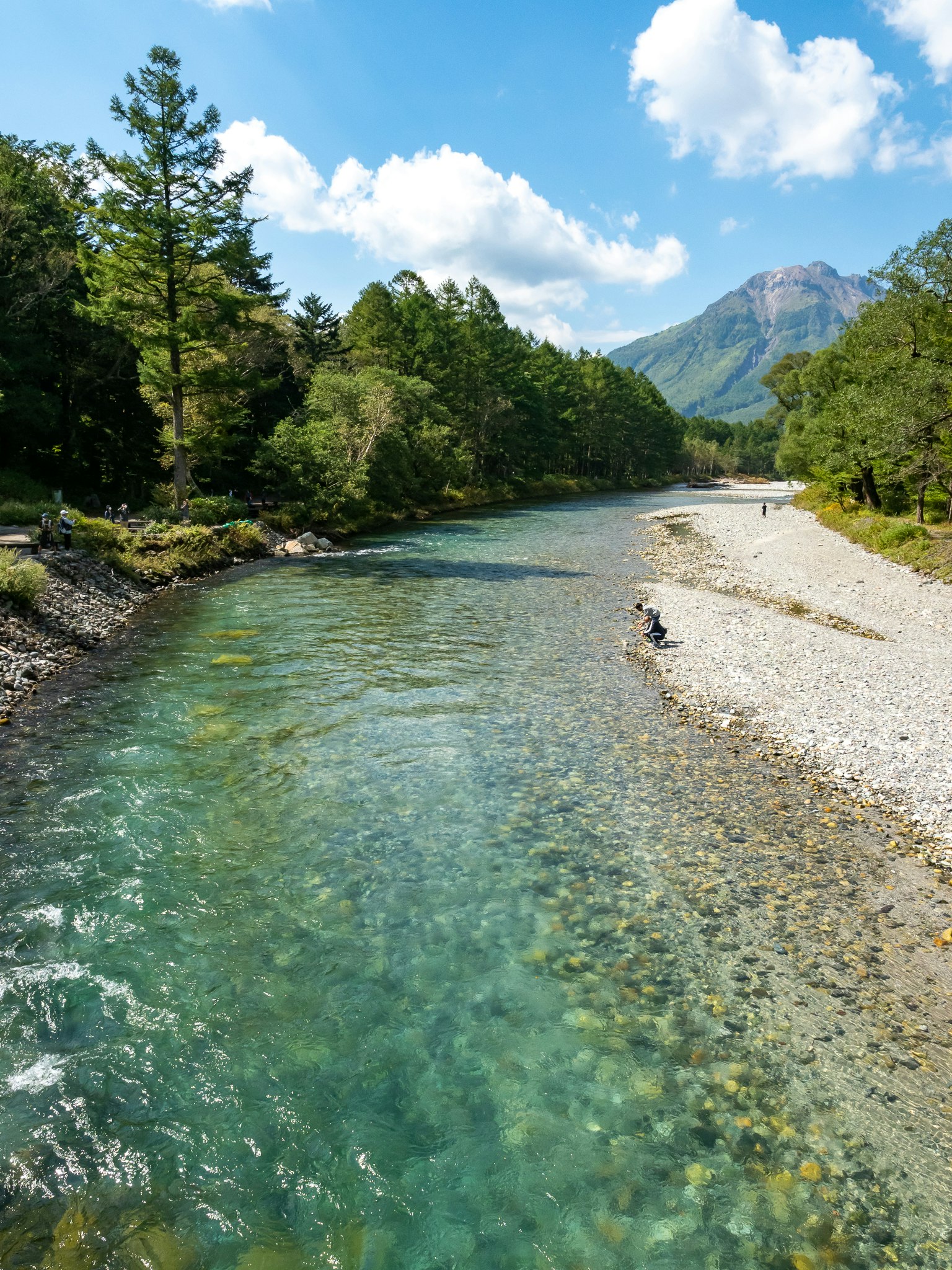 Klarer Fluss umgeben von üppigen Bäumen und Bergen