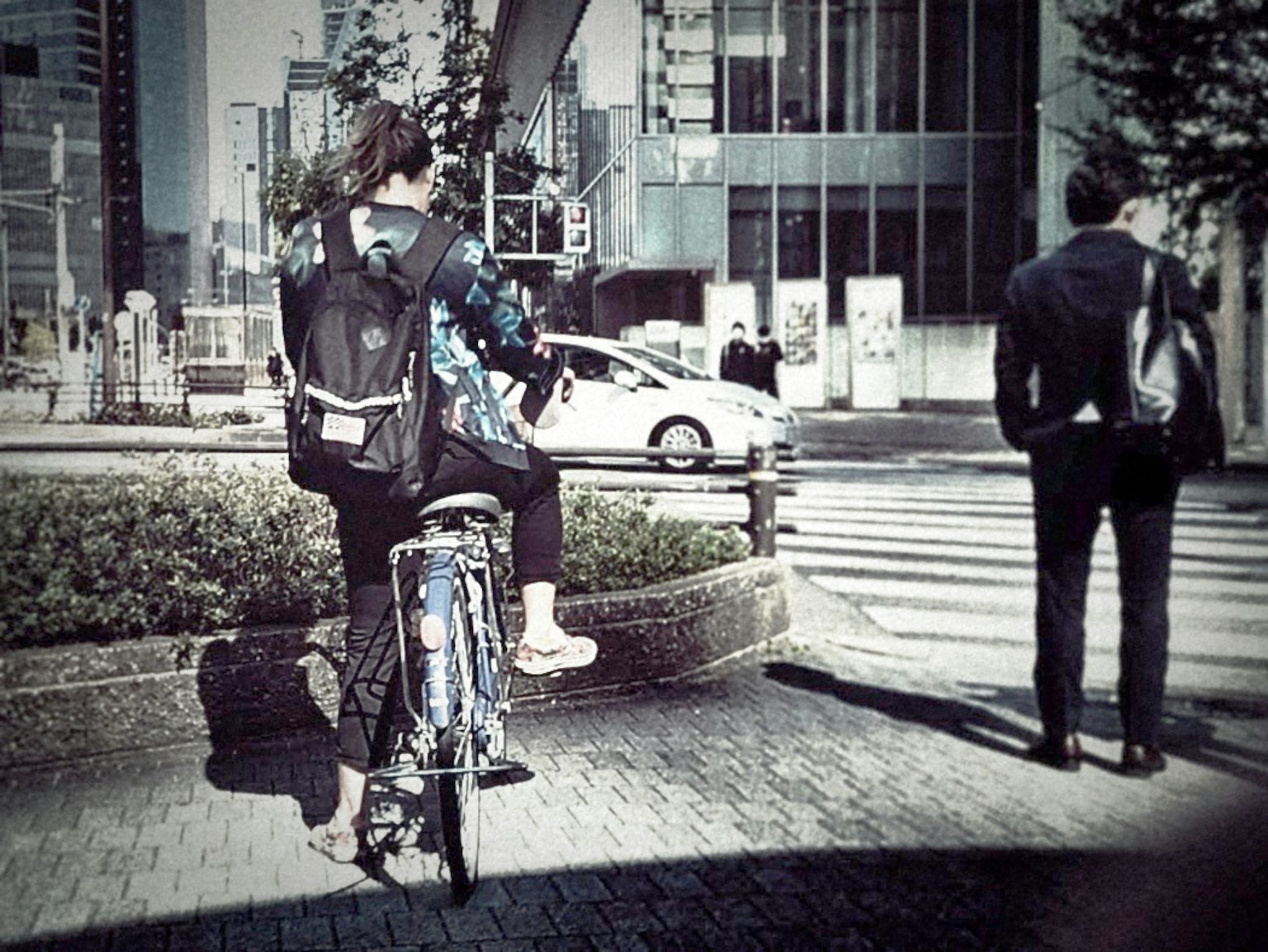 城市交叉口骑自行车的人和附近走路的商人