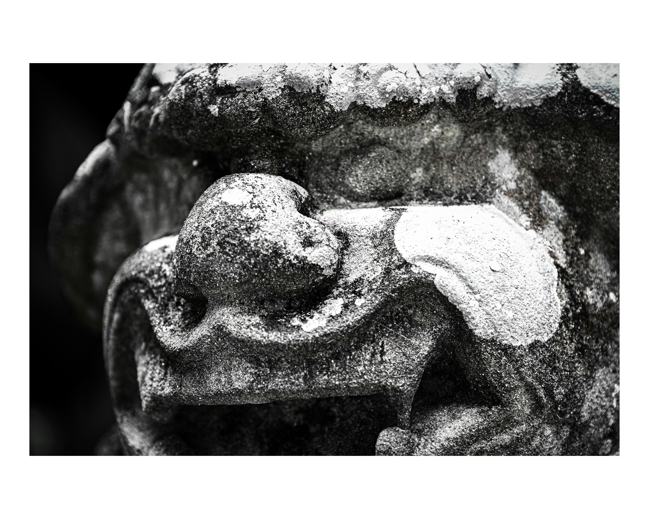 black-and-white close-up of a stone statue hand and drapery carving