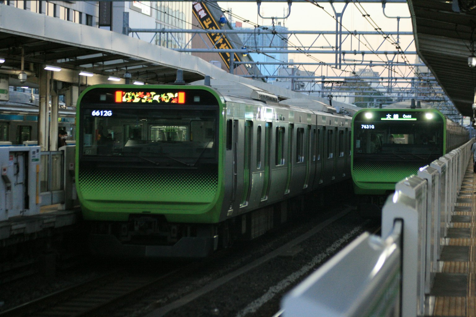 Green trains at a station during dusk