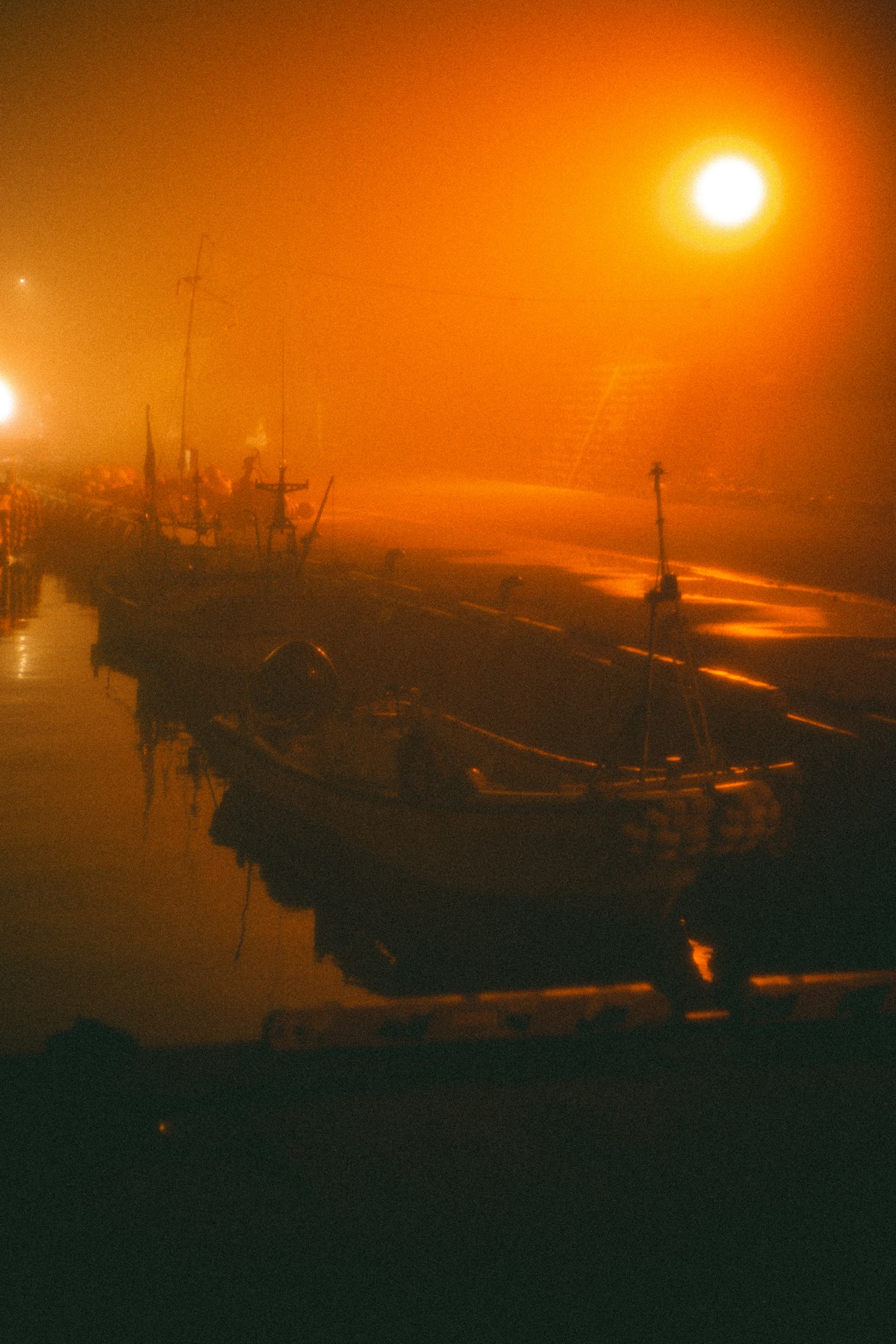 Barche nella nebbia con luce arancione