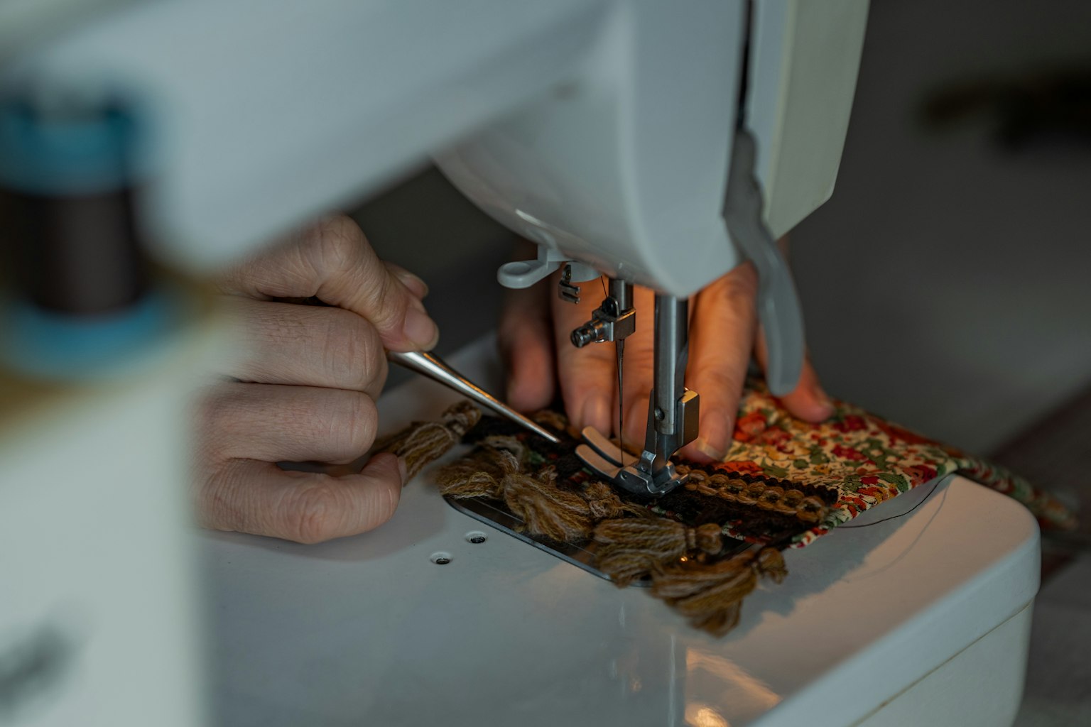 Primo piano di mani che cuciono tessuto con una macchina da cucire