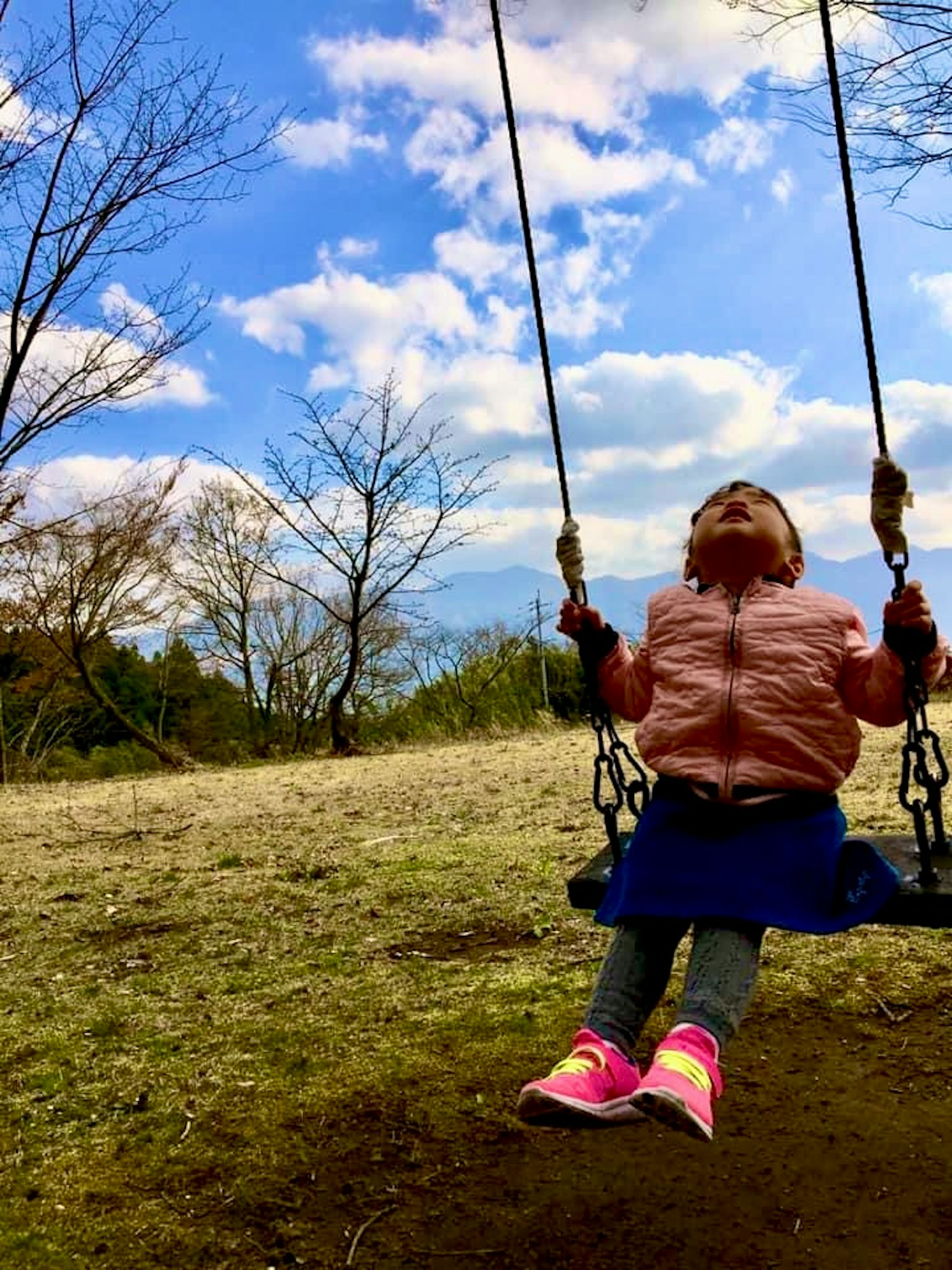 Enfant se balançant dans un parc sous un ciel bleu