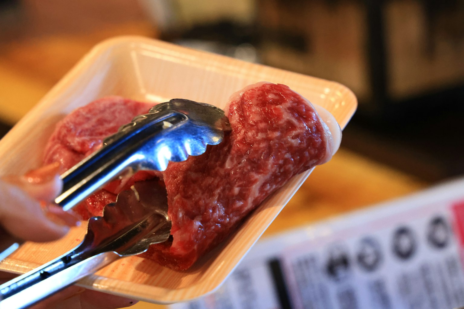 用夹子夹住的白色托盘中的新鲜肉块