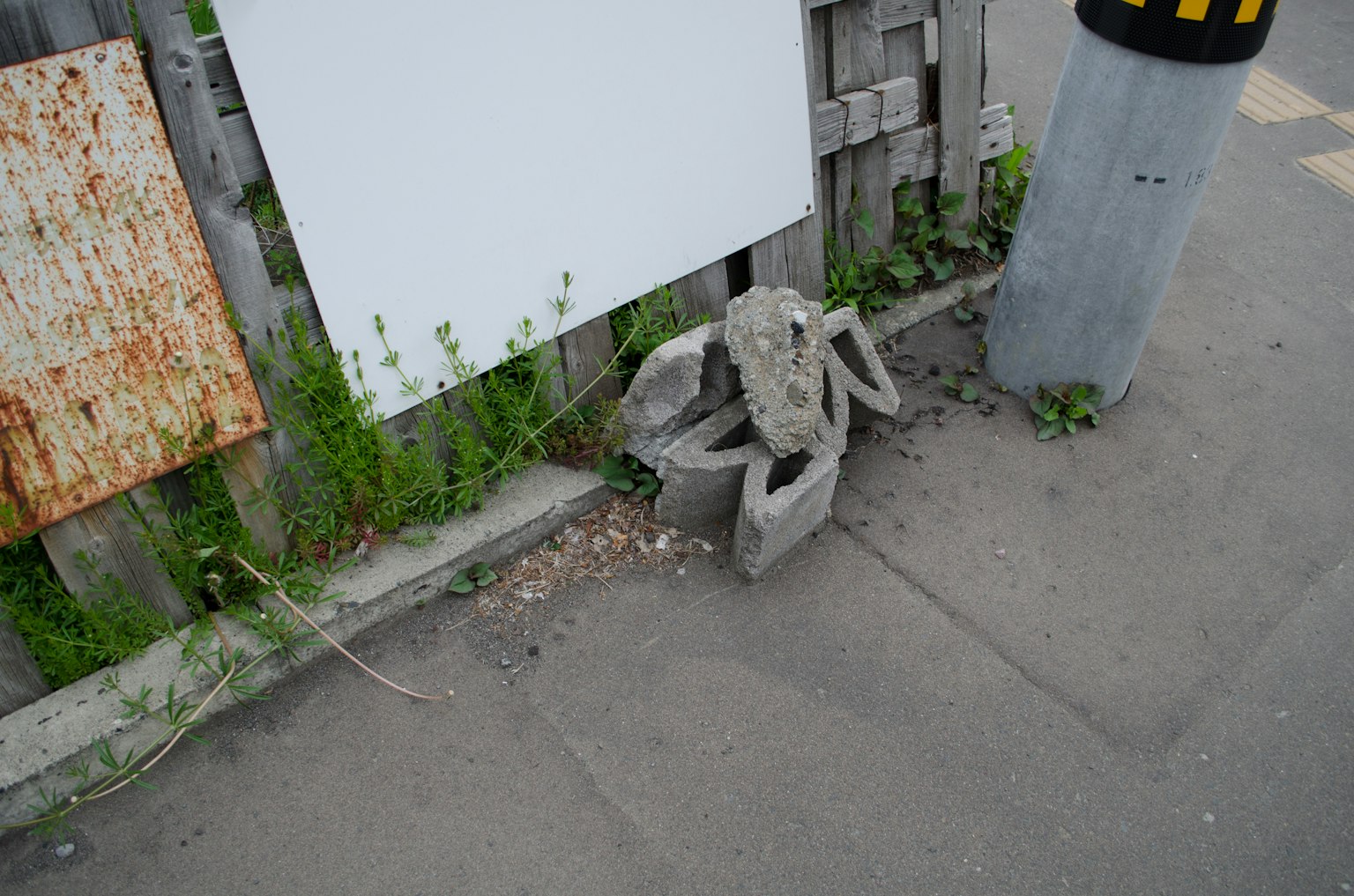 A concrete crab sculpture placed among grass near a wooden fence