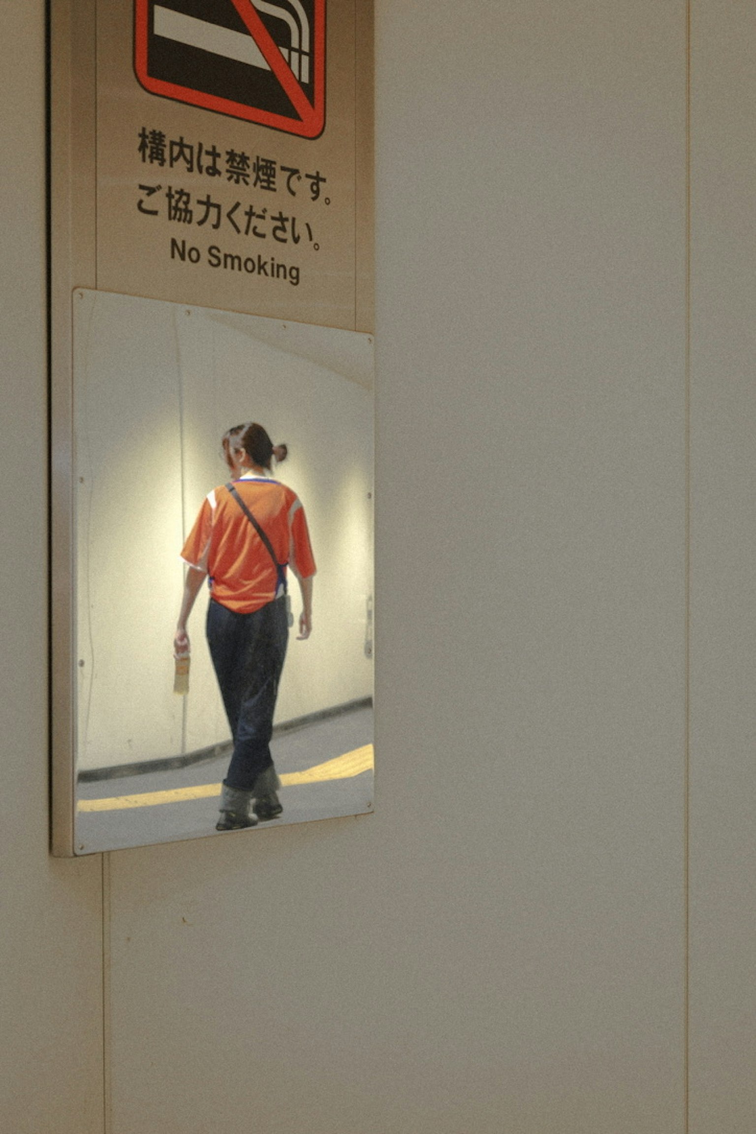Eine Person in einem orangefarbenen Hemd, die in einem Spiegel geht