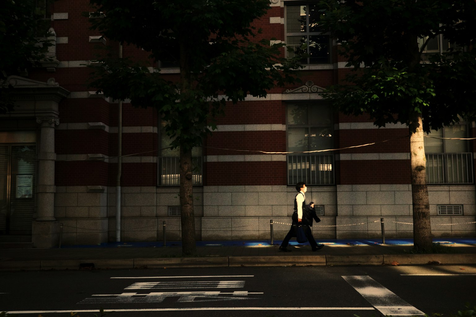 A man walking on a dimly lit street with silhouetted trees