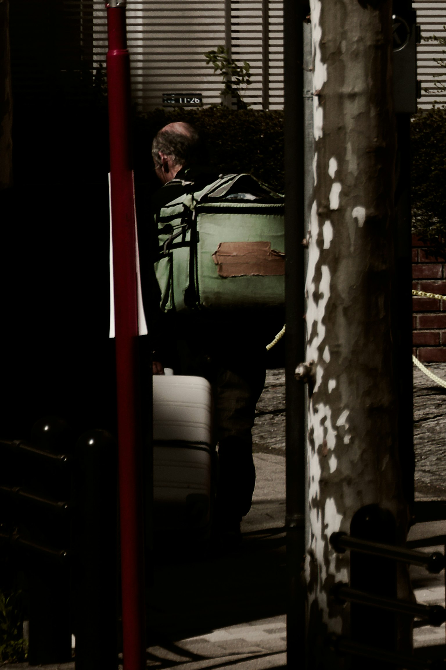 Eine Person mit einer grünen Tasche vor einem dunklen Hintergrund