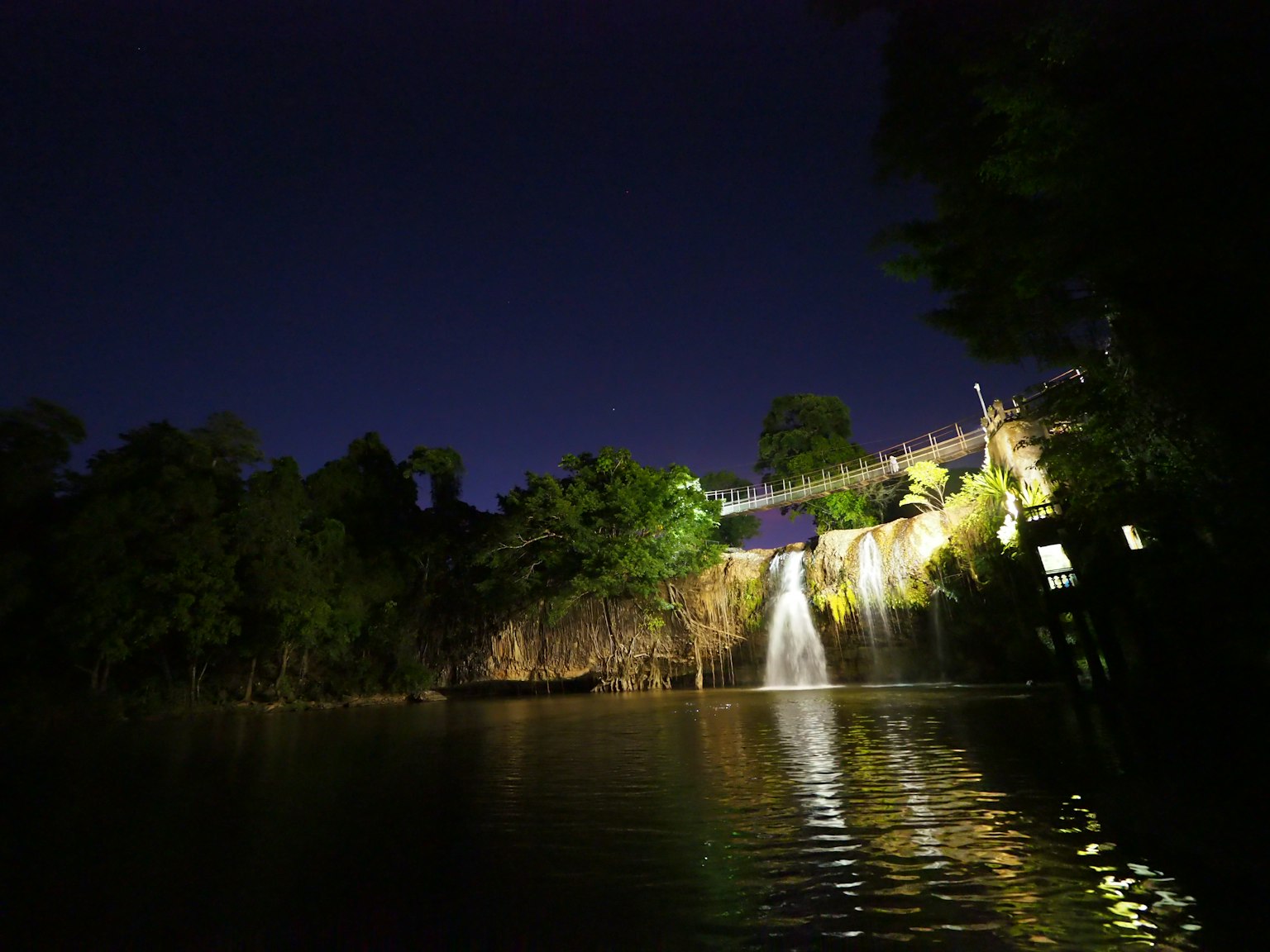 Una cascada serena iluminada por la noche rodeada de exuberante vegetación