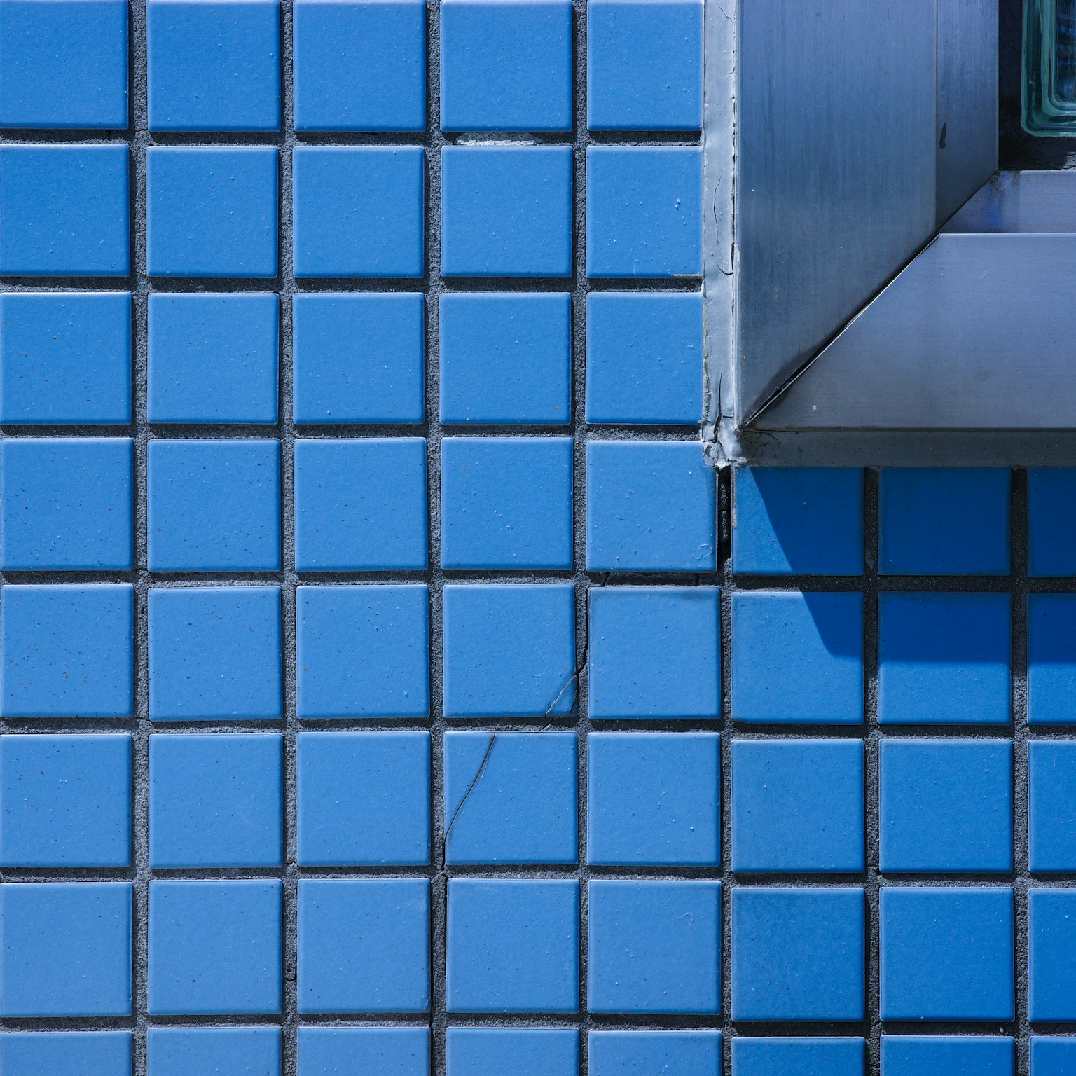 Teil einer blauen Fliesenwand mit einer Metallkante