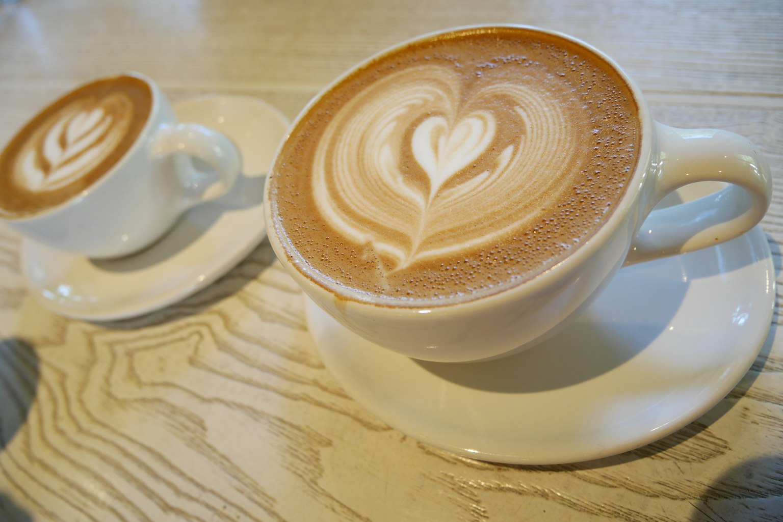 Cappuccino with heart latte art and a small coffee cup