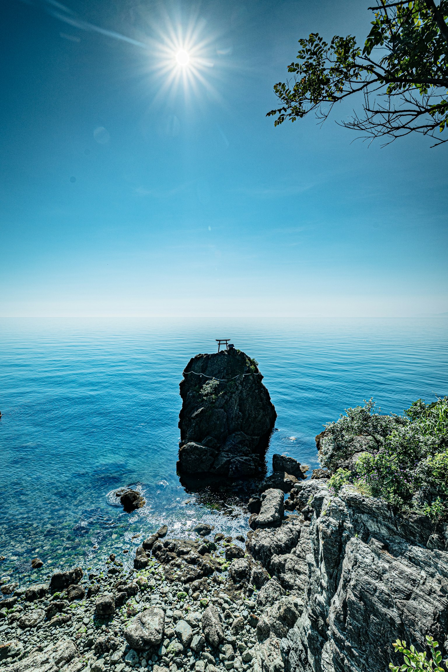 Scenic view of blue ocean and rocky shore bright sun shining