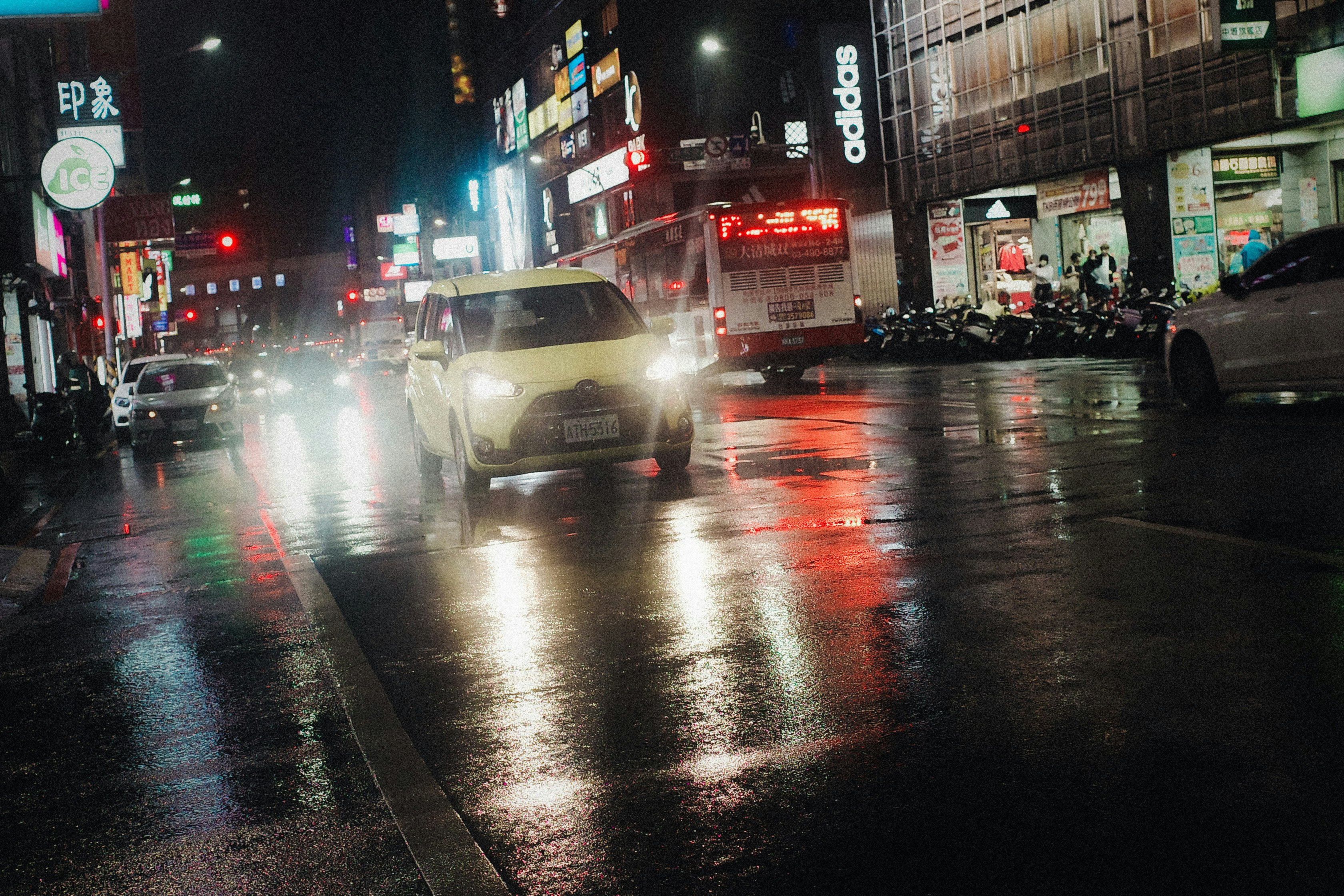 雨の夜の繁華街で走る車のテールライト