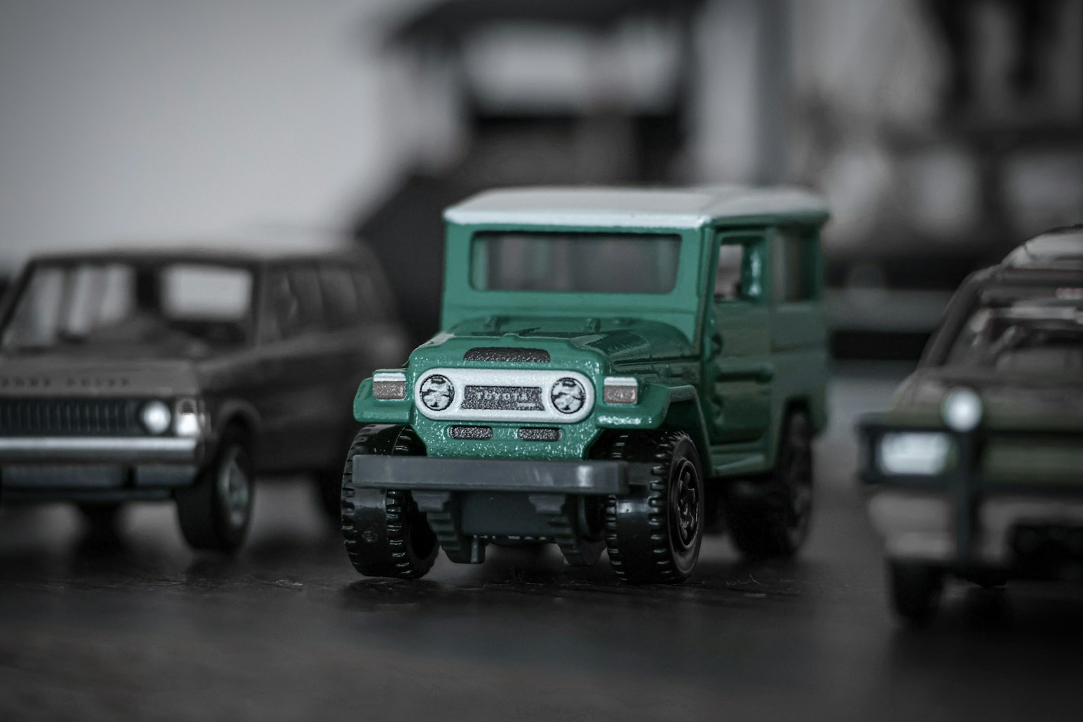 Une voiture jouet verte au premier plan avec d'autres voitures jouets floues en arrière-plan