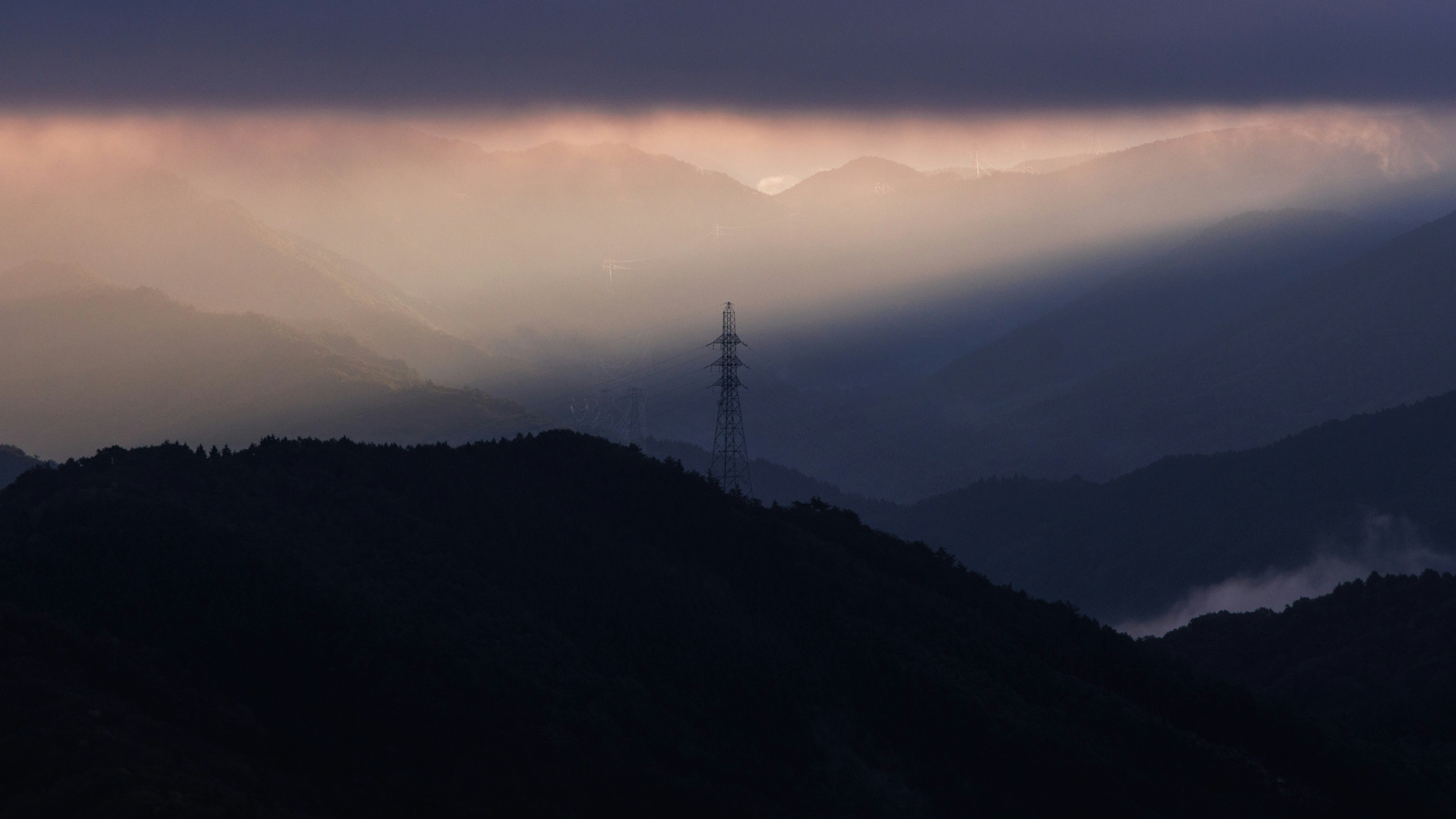 山稜と送電鉄塔が見える夕暮れの霧の風景