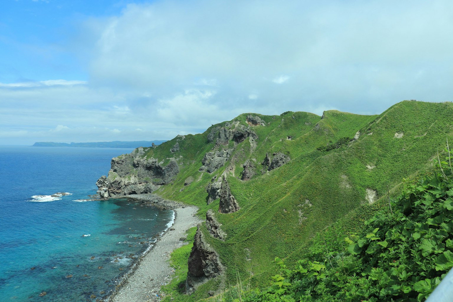 Scenic view of green hills and blue ocean