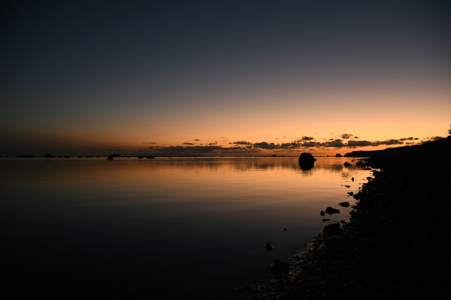 Coucher de soleil tranquille sur une mer calme avec une côte sereine