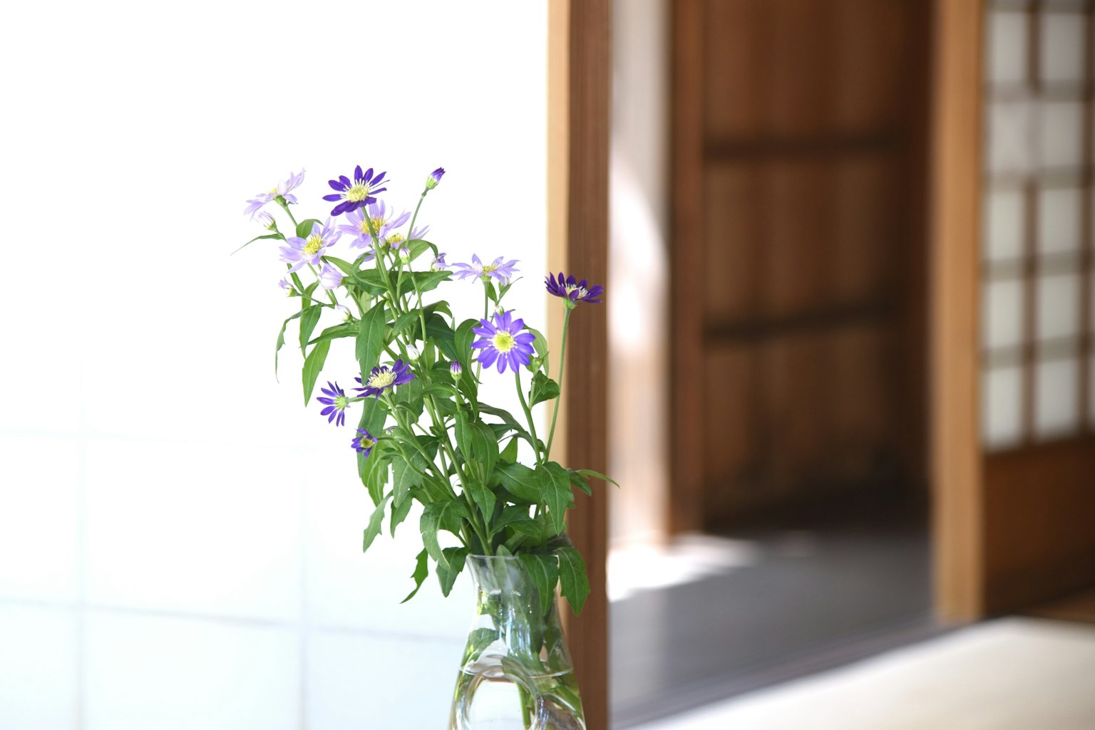 방 안에 놓인 보라색 꽃이 있는 유리 꽃병