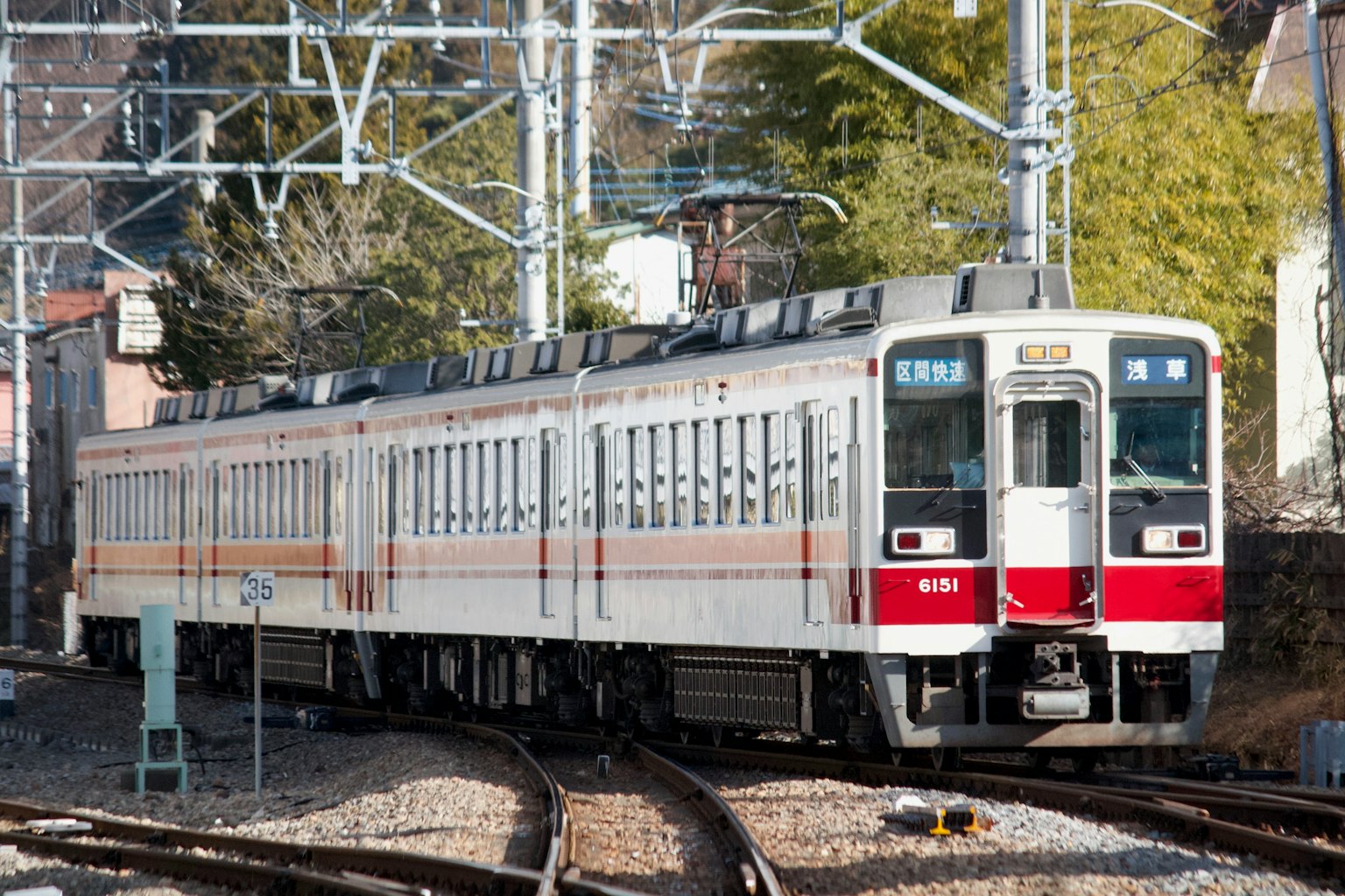 A white and red train is stopped at a railway junction