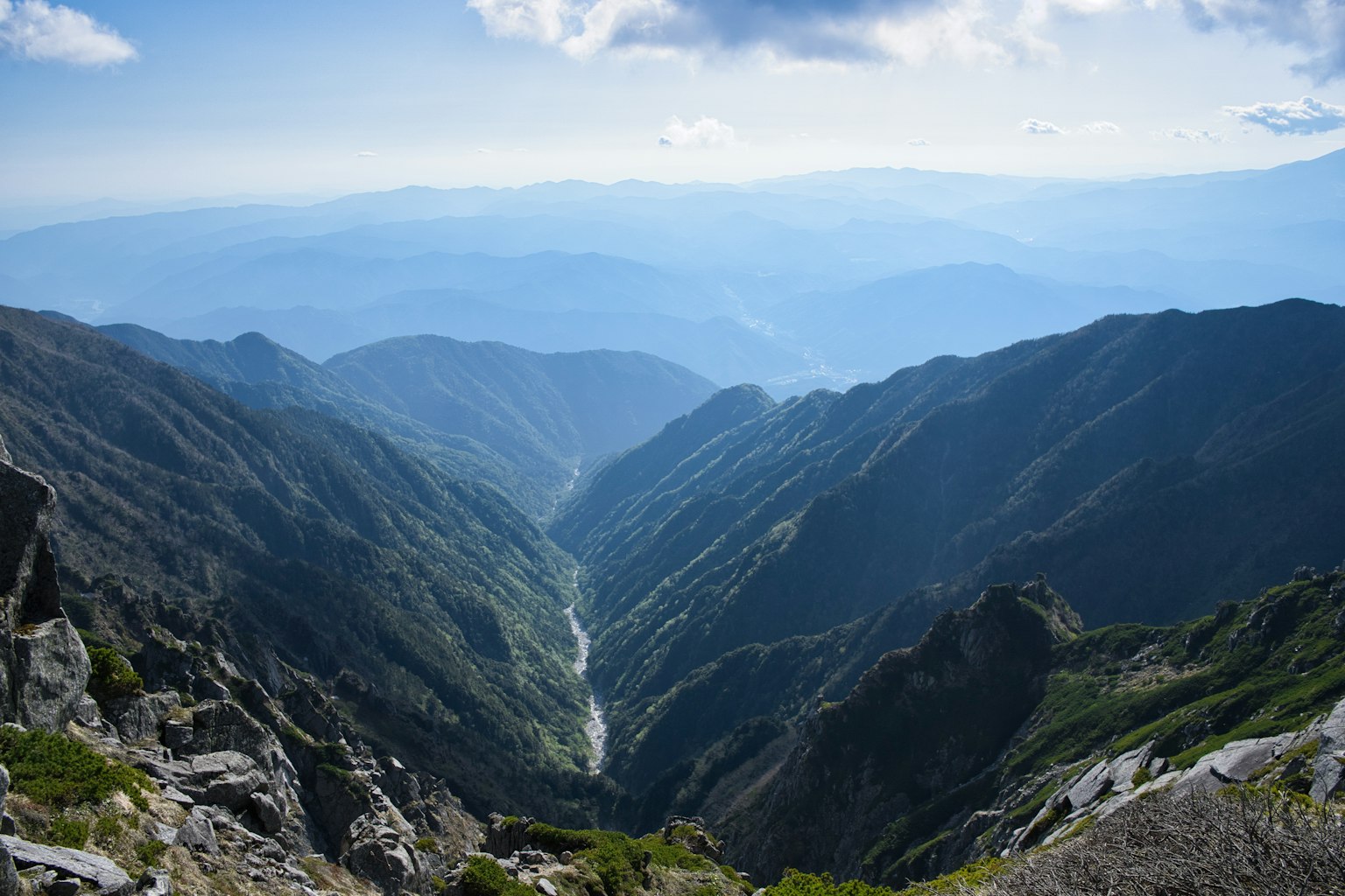 Vista mozzafiato di una valle montana con picchi rocciosi e orizzonti lontani