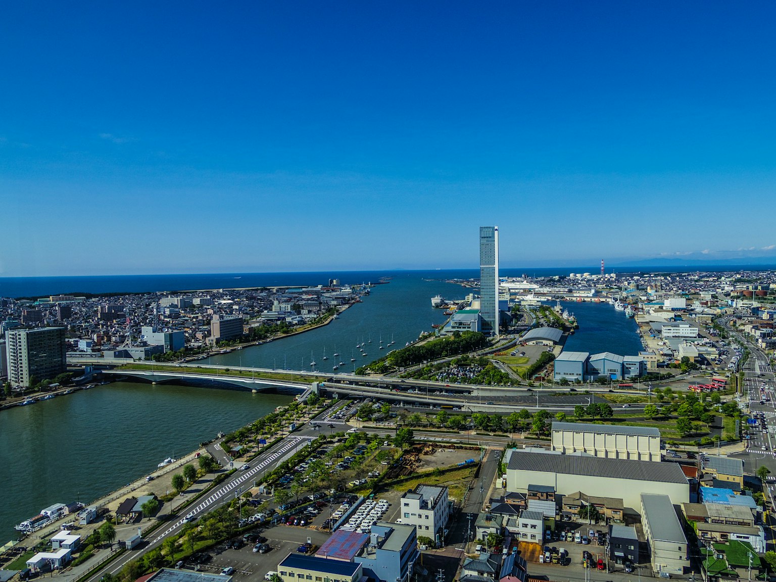 Vue aérienne d'une ville avec ciel bleu et rivière présentant de grands bâtiments et un pont