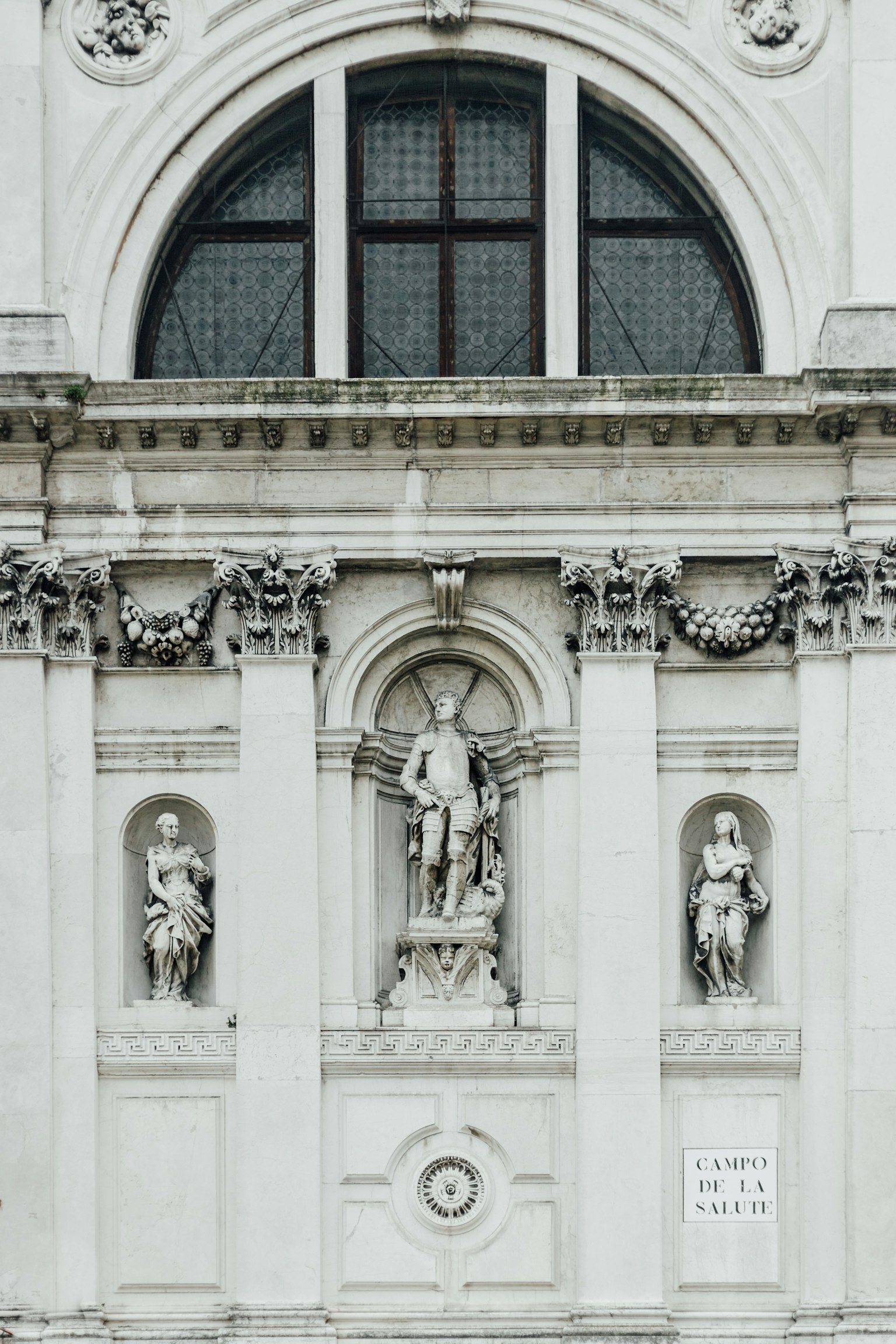 Facade of a white building featuring sculptures and decorative windows
