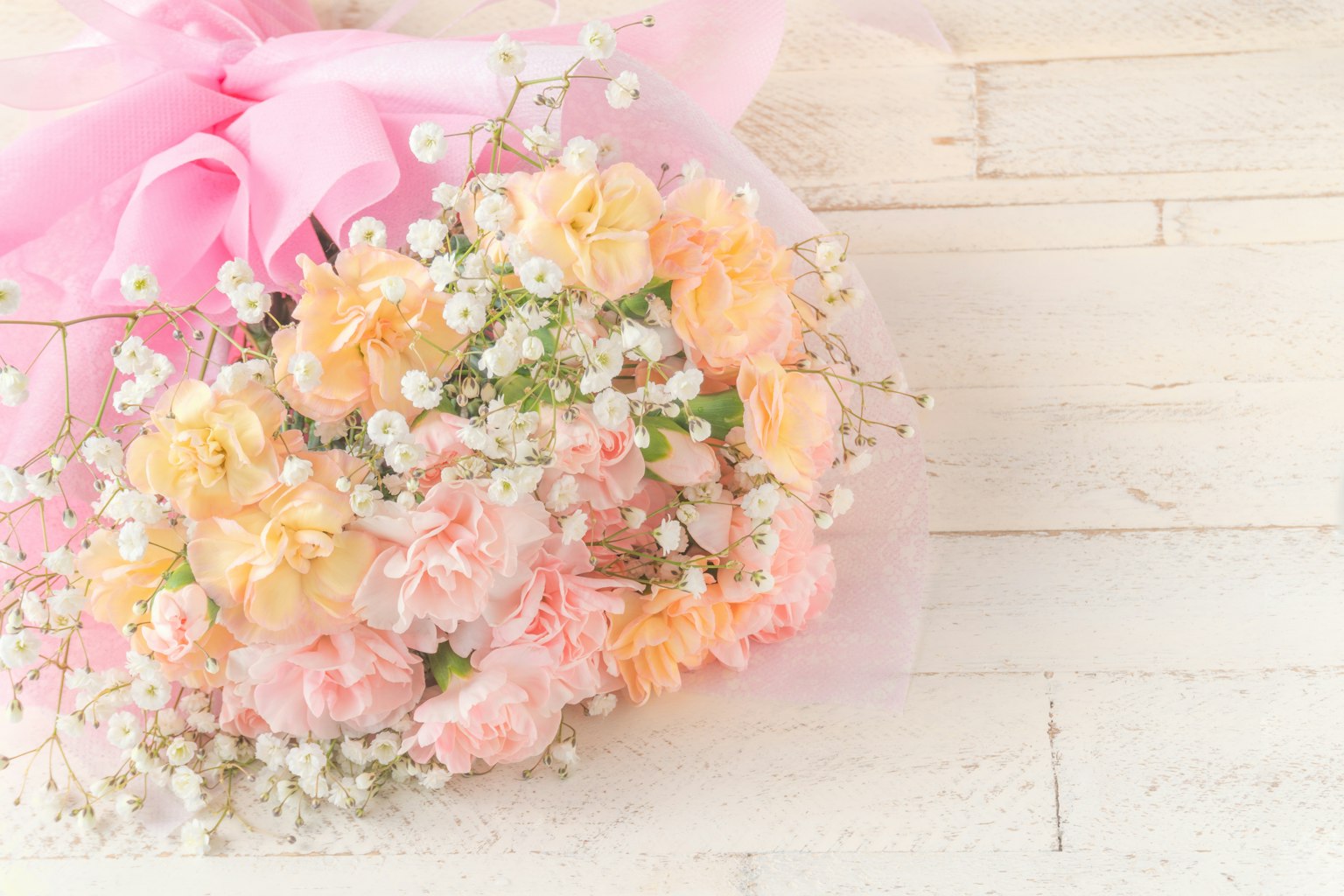 Bouquet de roses pastel avec des gypsophiles sur une table en bois