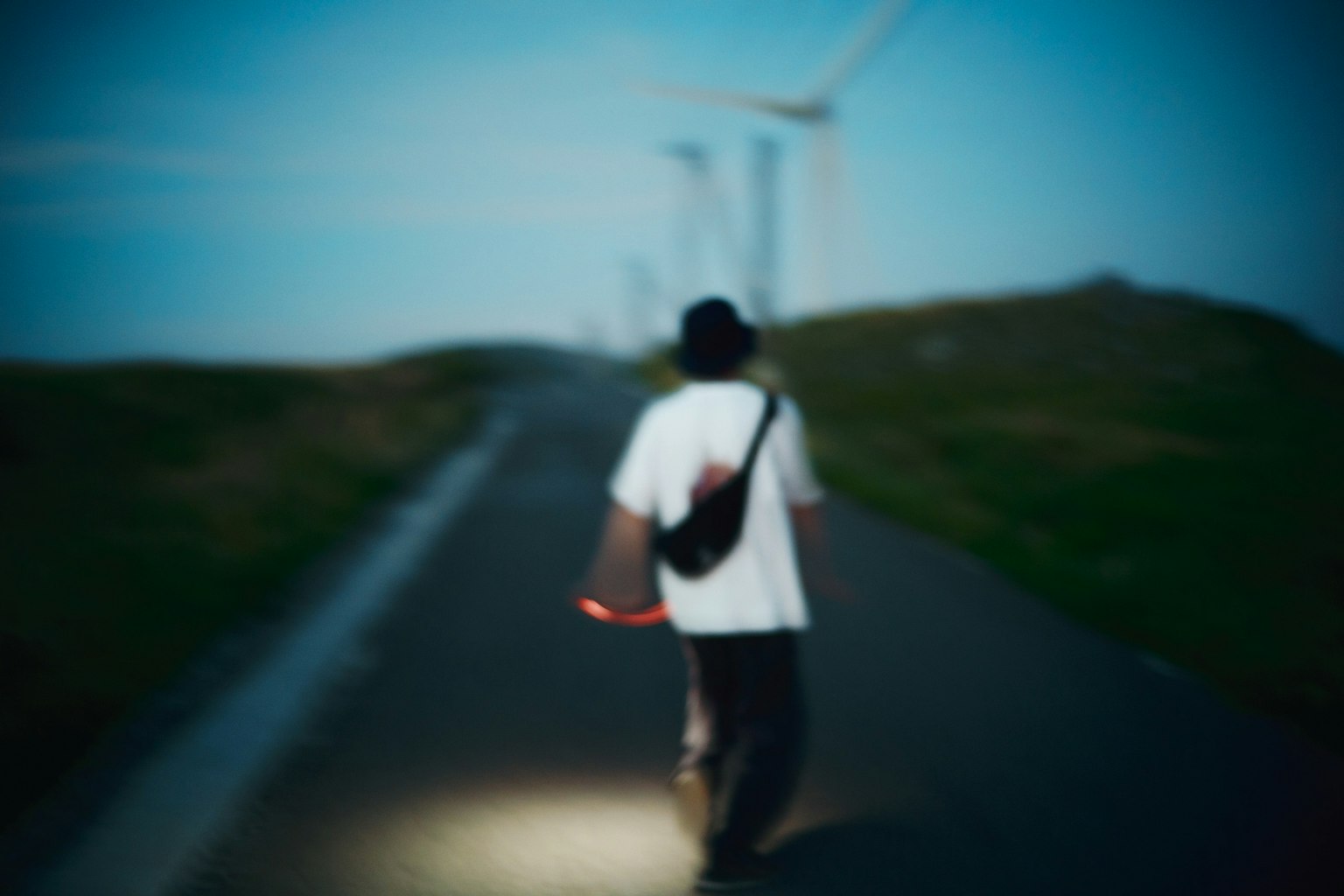 風力発電機のある道を歩く人物のぼやけた画像