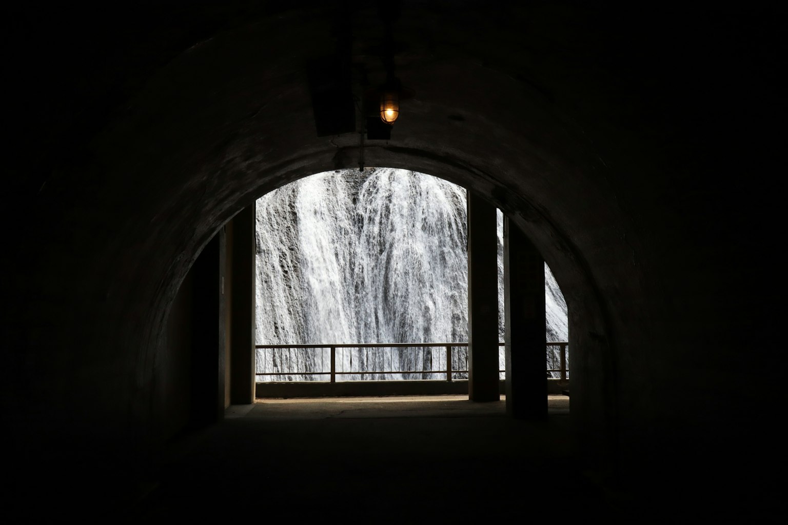 Vista di una cascata attraverso un arco di tunnel con illuminazione ambientale