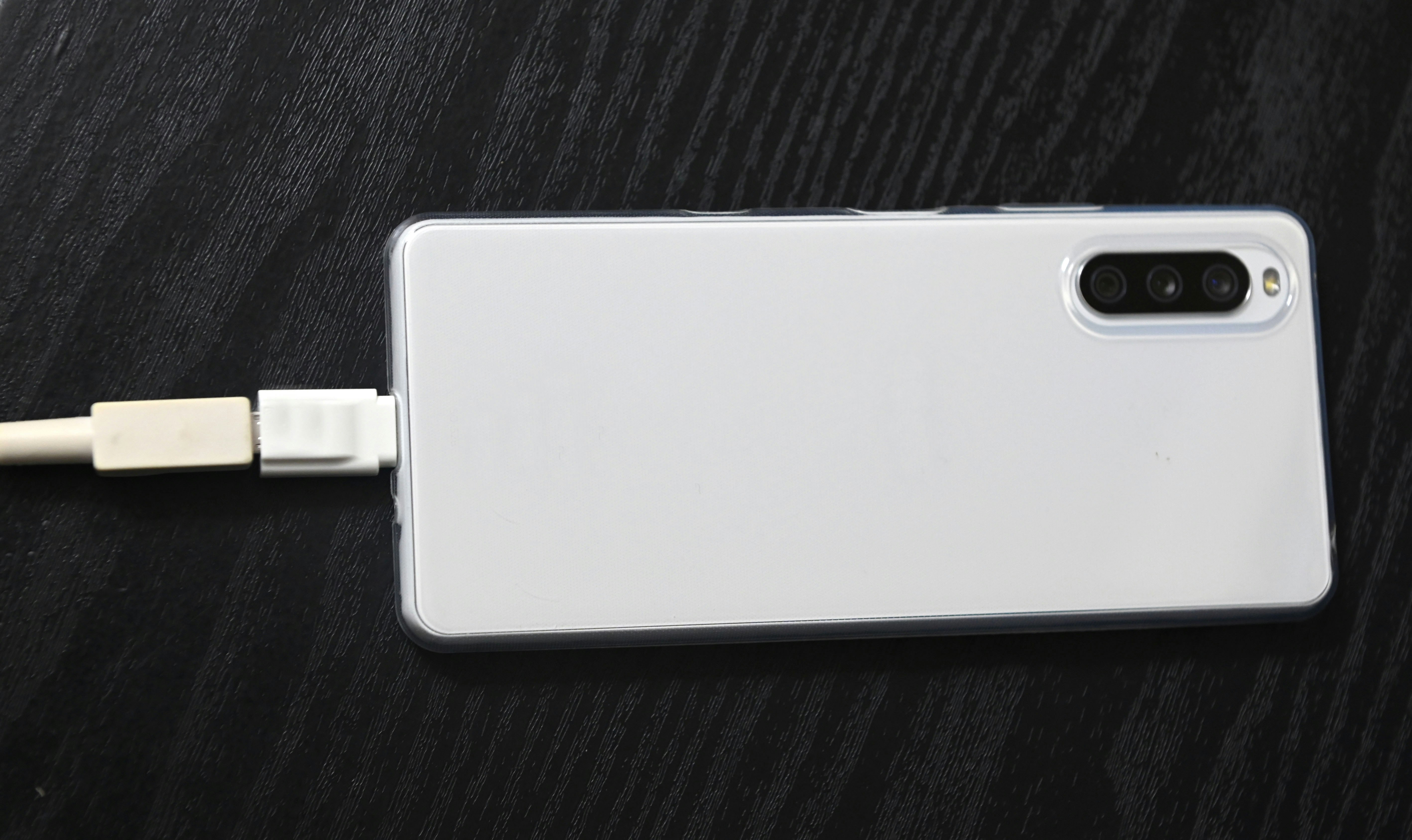 smartphone blanc avec câble de charge sur un bureau
