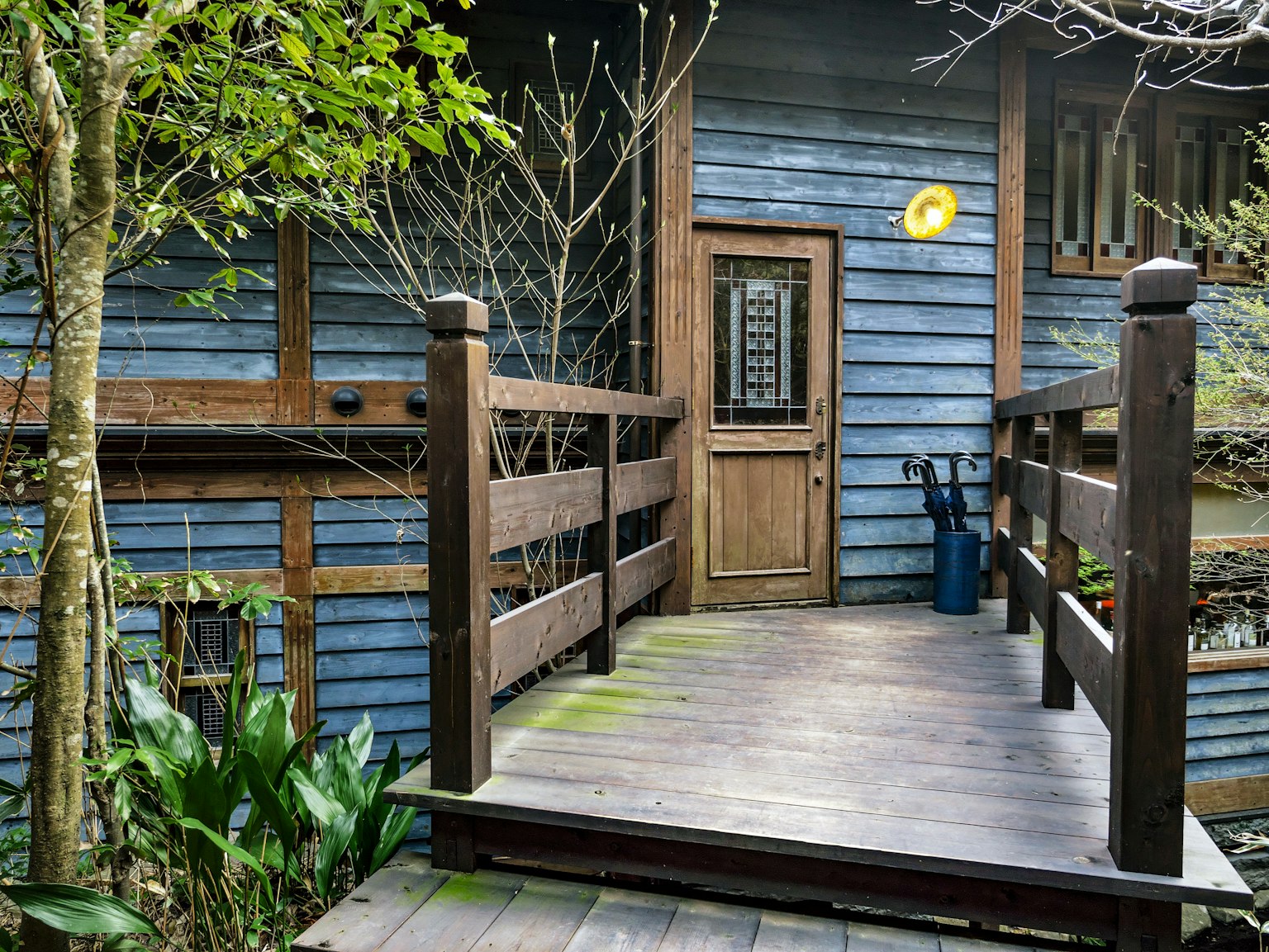 Entrance to a small house with blue wooden exterior and wooden deck