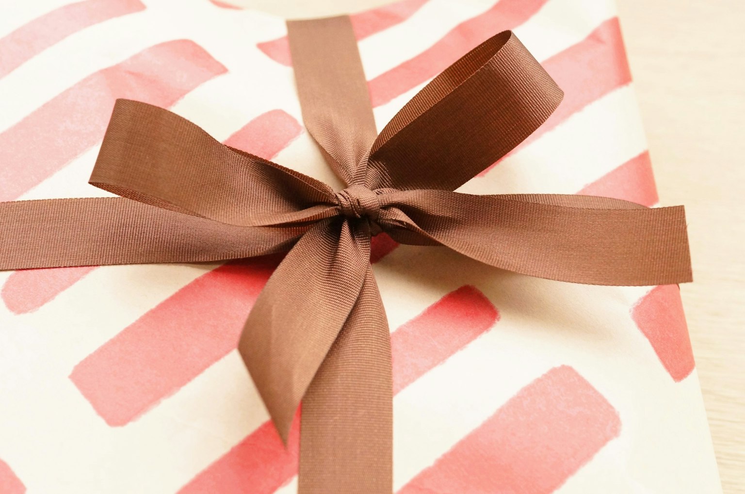 Geschenk eingewickelt in rotes gestreiftes Papier mit braunem Band