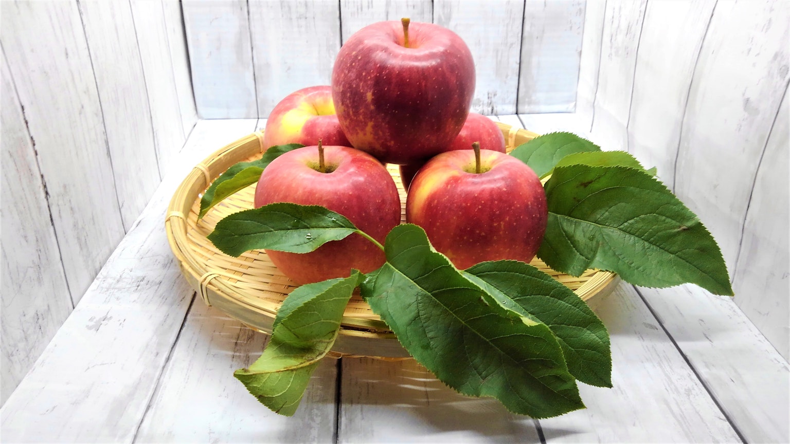 Manzanas rojas en una canasta con hojas verdes