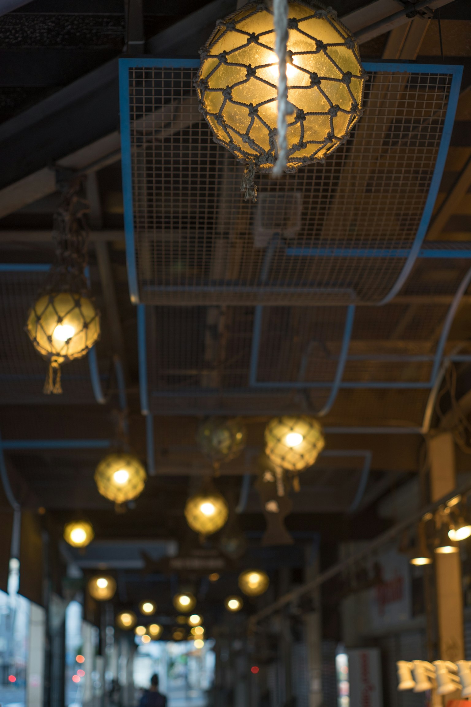Indoor corridor featuring round lamps suspended from a blue frame