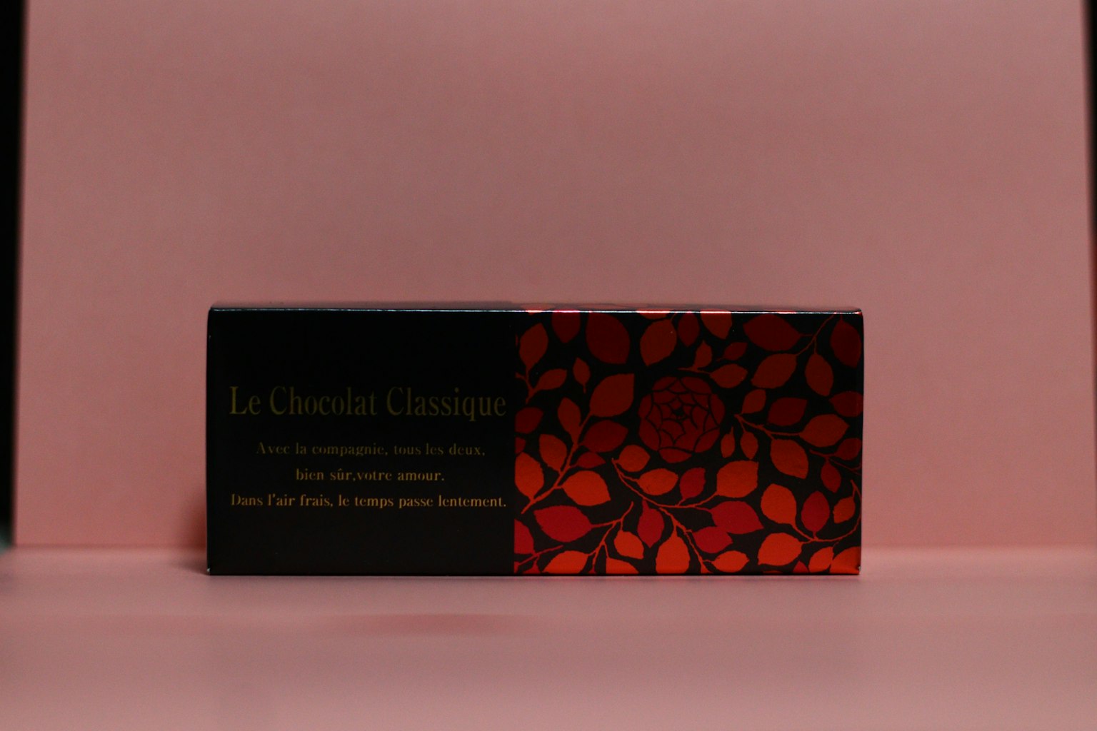 Embalaje negro con diseño de hojas rojas y elementos florales