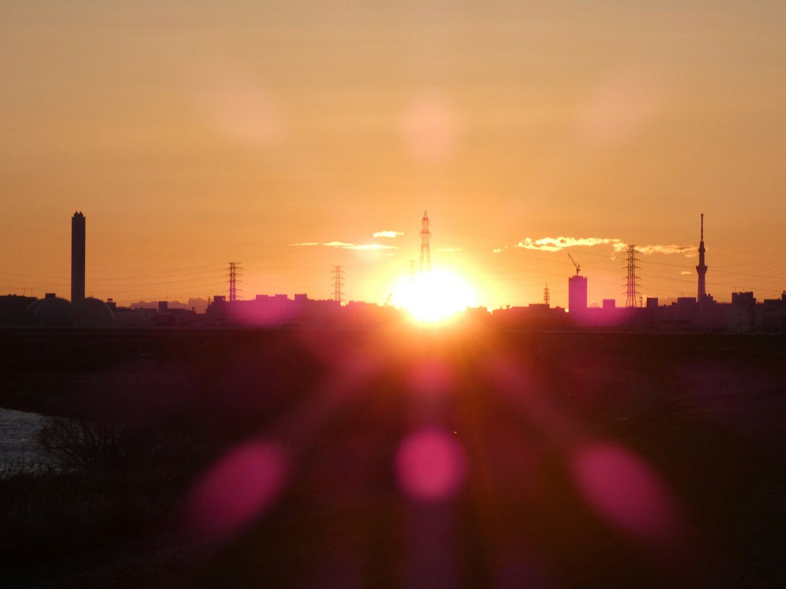 City skyline silhouette with sunset and light flare