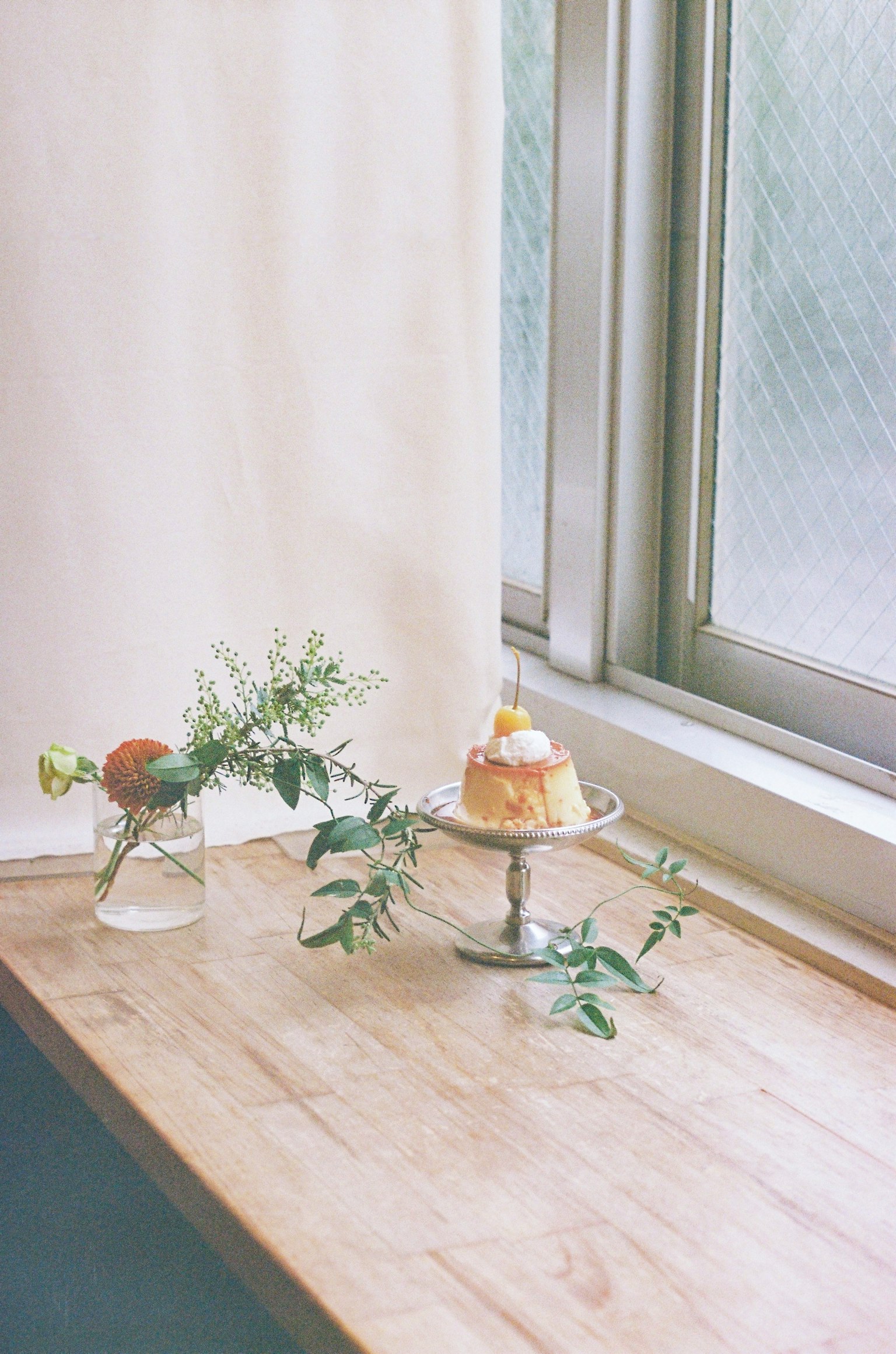 Tavolo in legno vicino alla finestra con una torta e un vaso di fiori