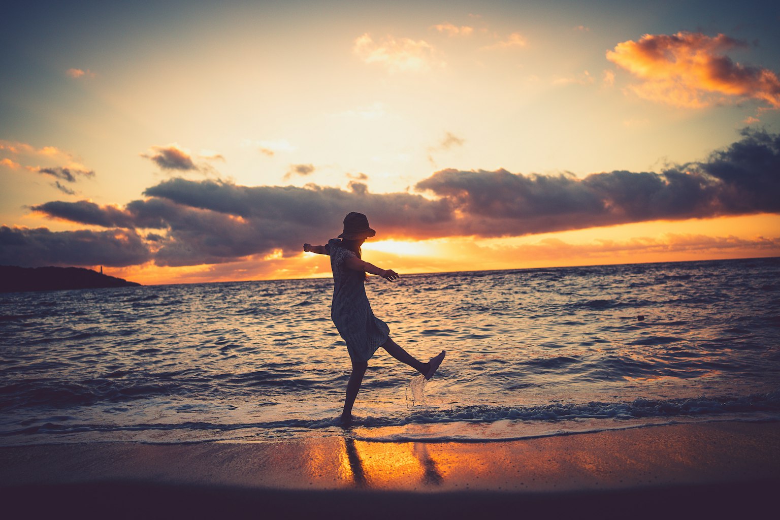 Persona disfrutando en la playa con el atardecer de fondo