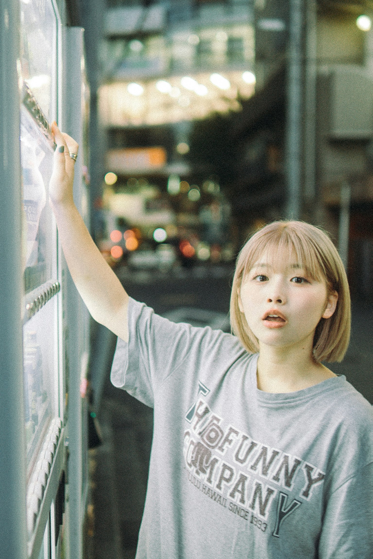 年轻女性看着街道标志，穿着灰色T恤，短发