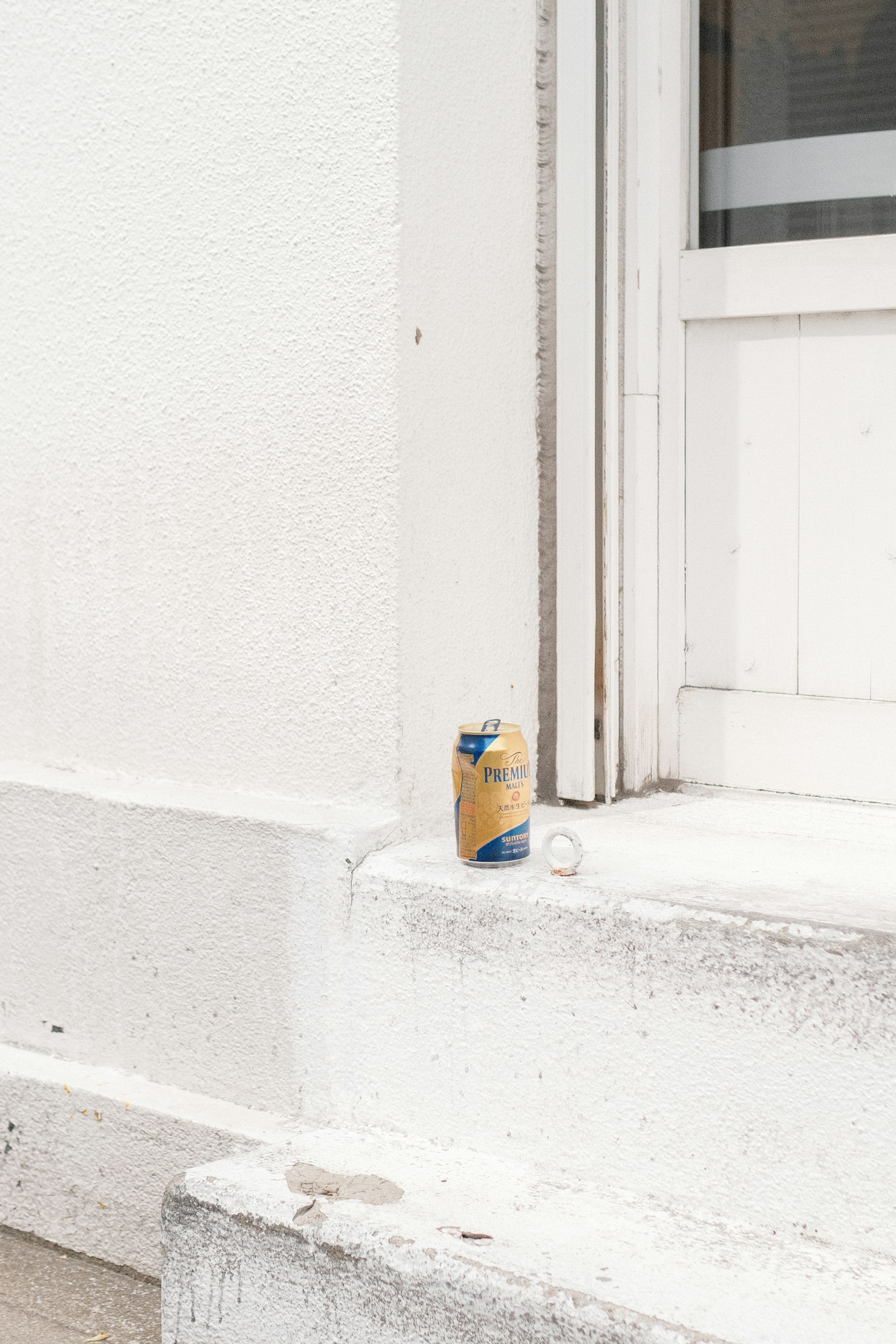Una lattina e una bottiglia trasparente davanti a un muro bianco