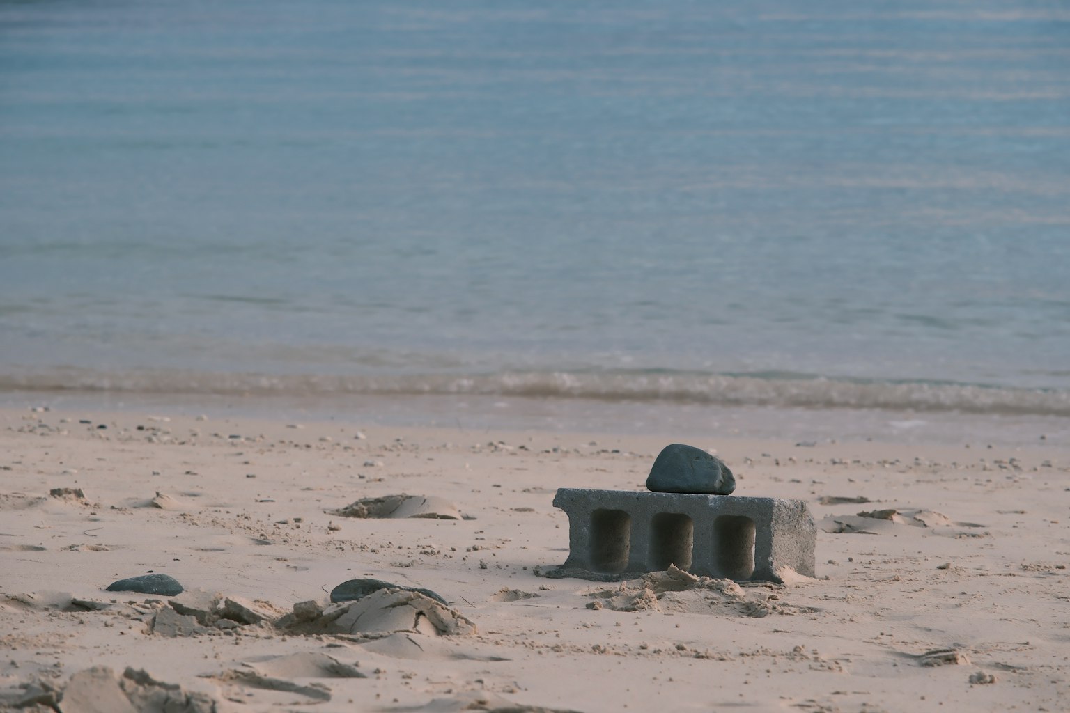 Bloc de béton sur la plage de sable avec une pierre dessus