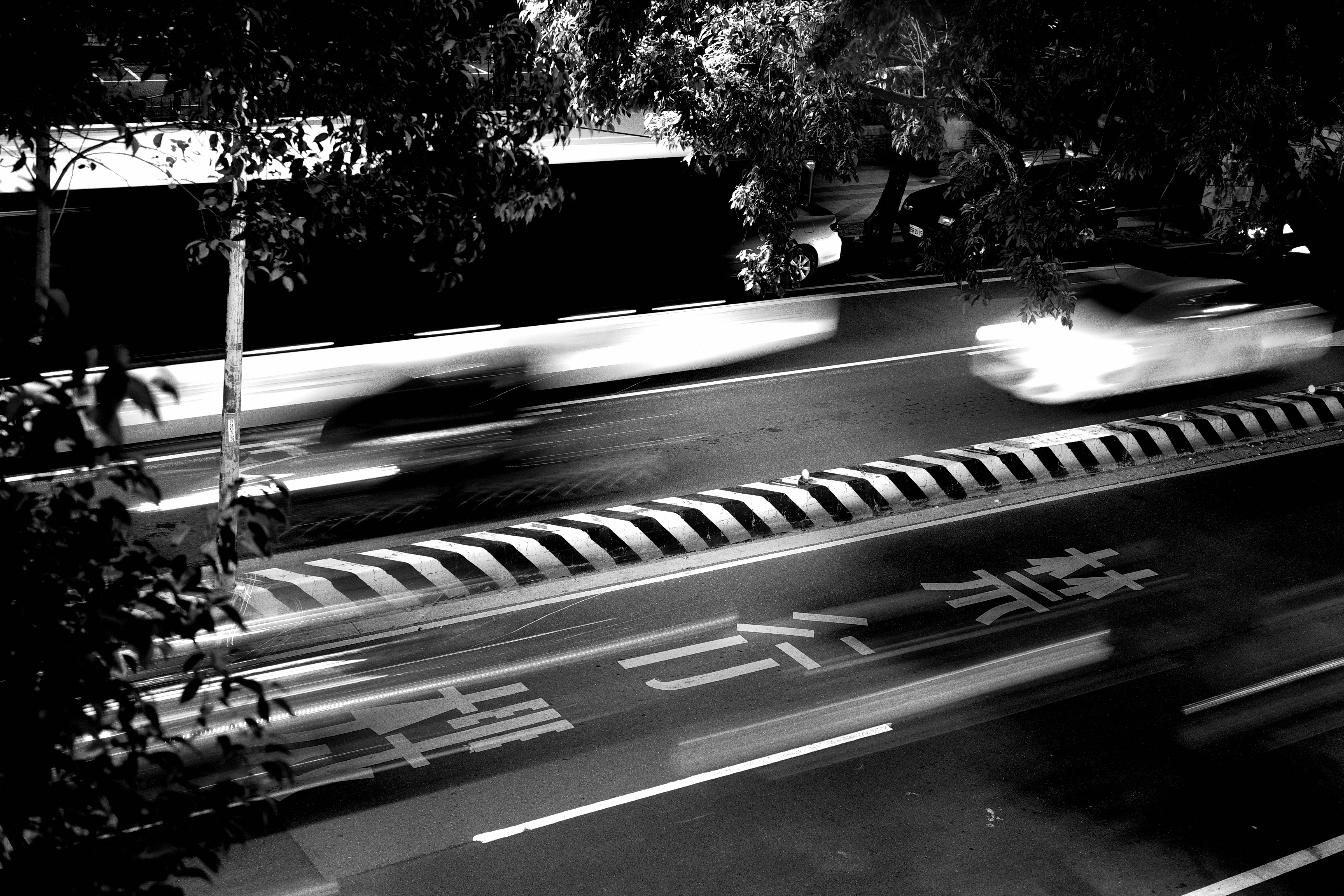 街路樹のある交差点を走る車の流し撮り
