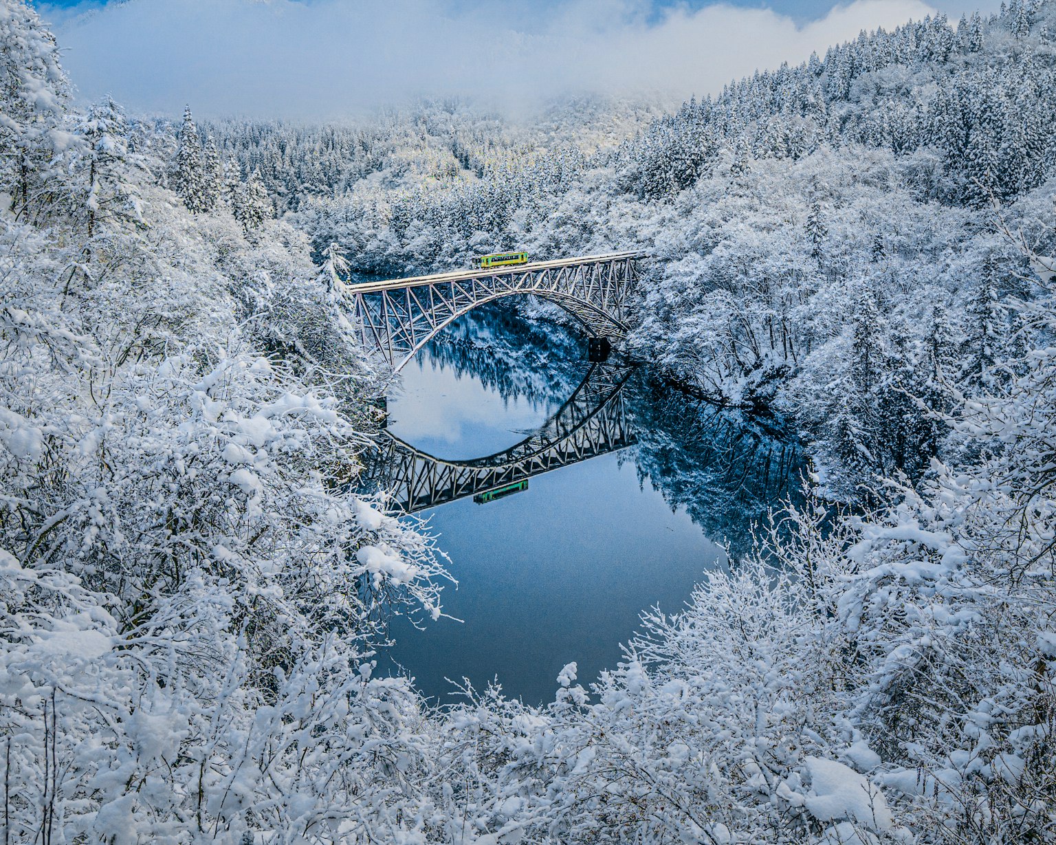 雪覆盖的桥横跨宁静的湖泊，四周环绕着冬季树木