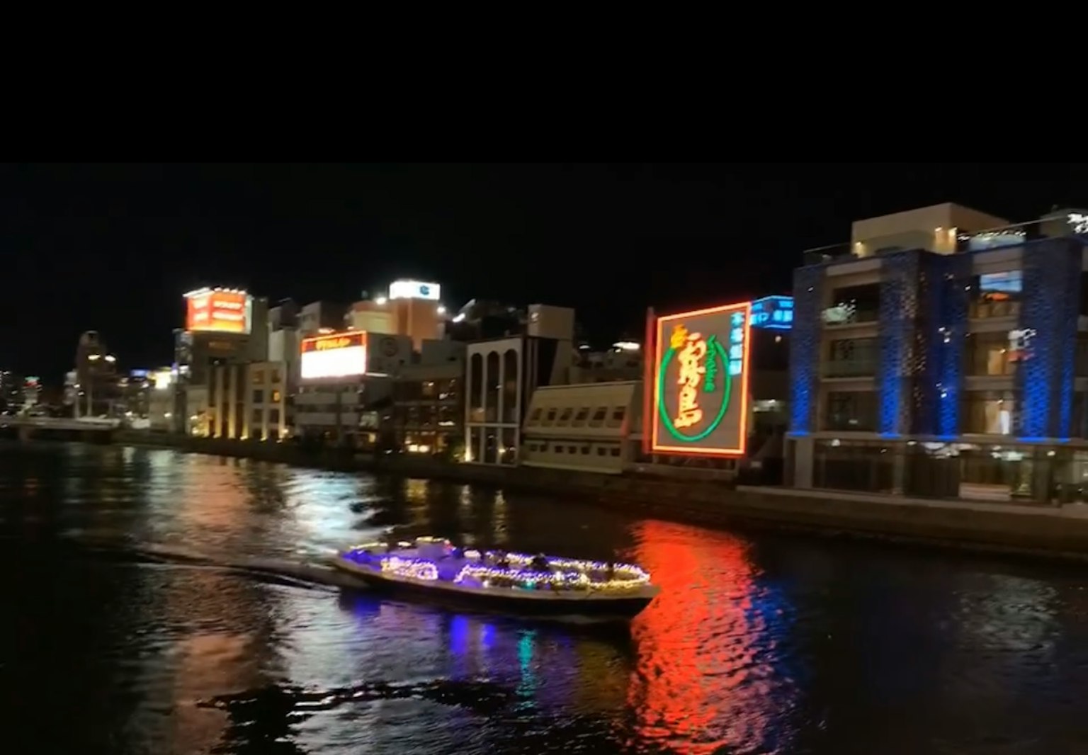 Night view of a sightseeing boat on the river with illuminated buildings