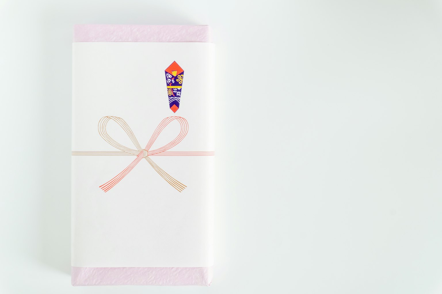 Un paquete blanco atado con una cinta rosa que presenta una etiqueta de helado